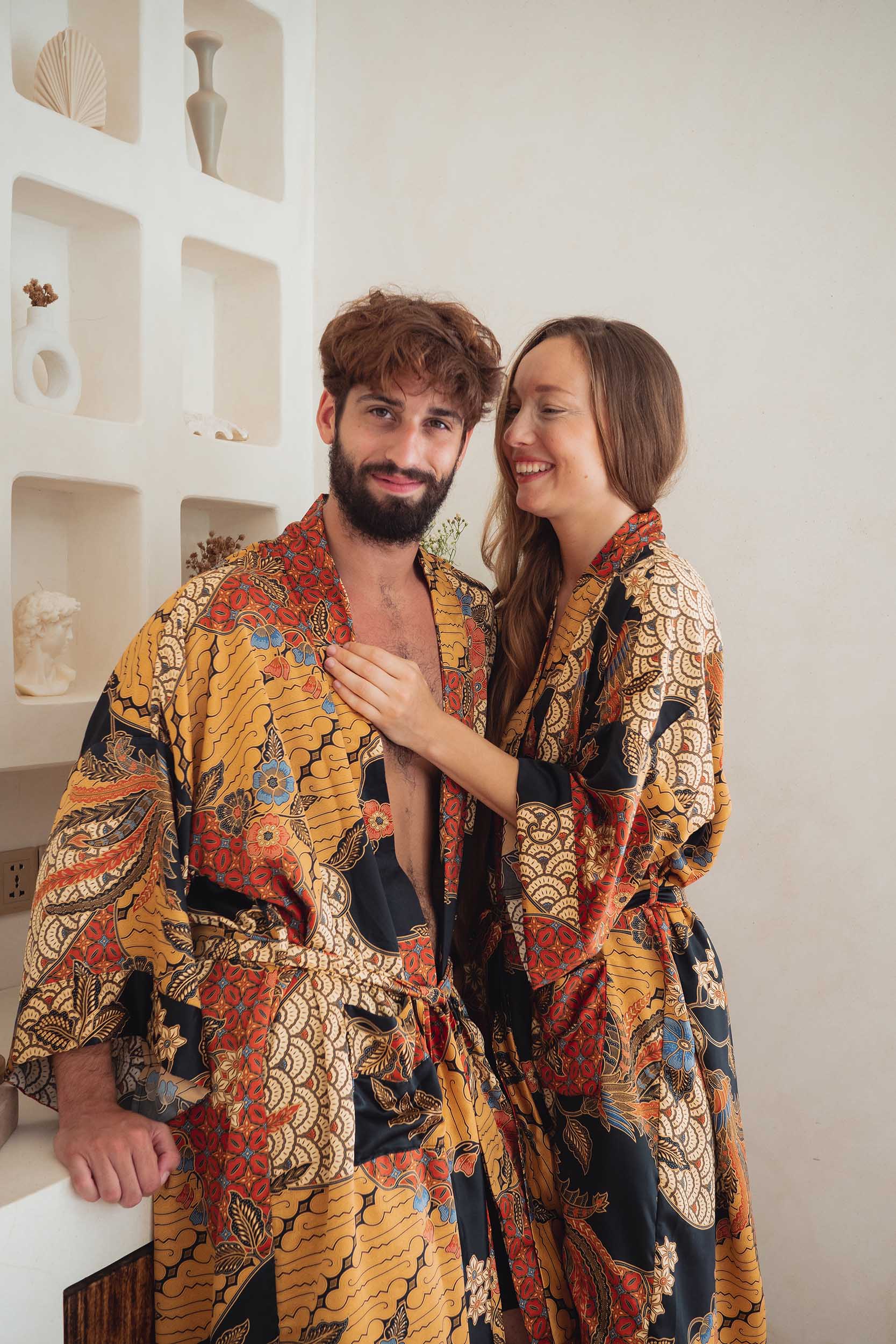 Two people wearing Agni kimono patterned robes standing close together indoors.