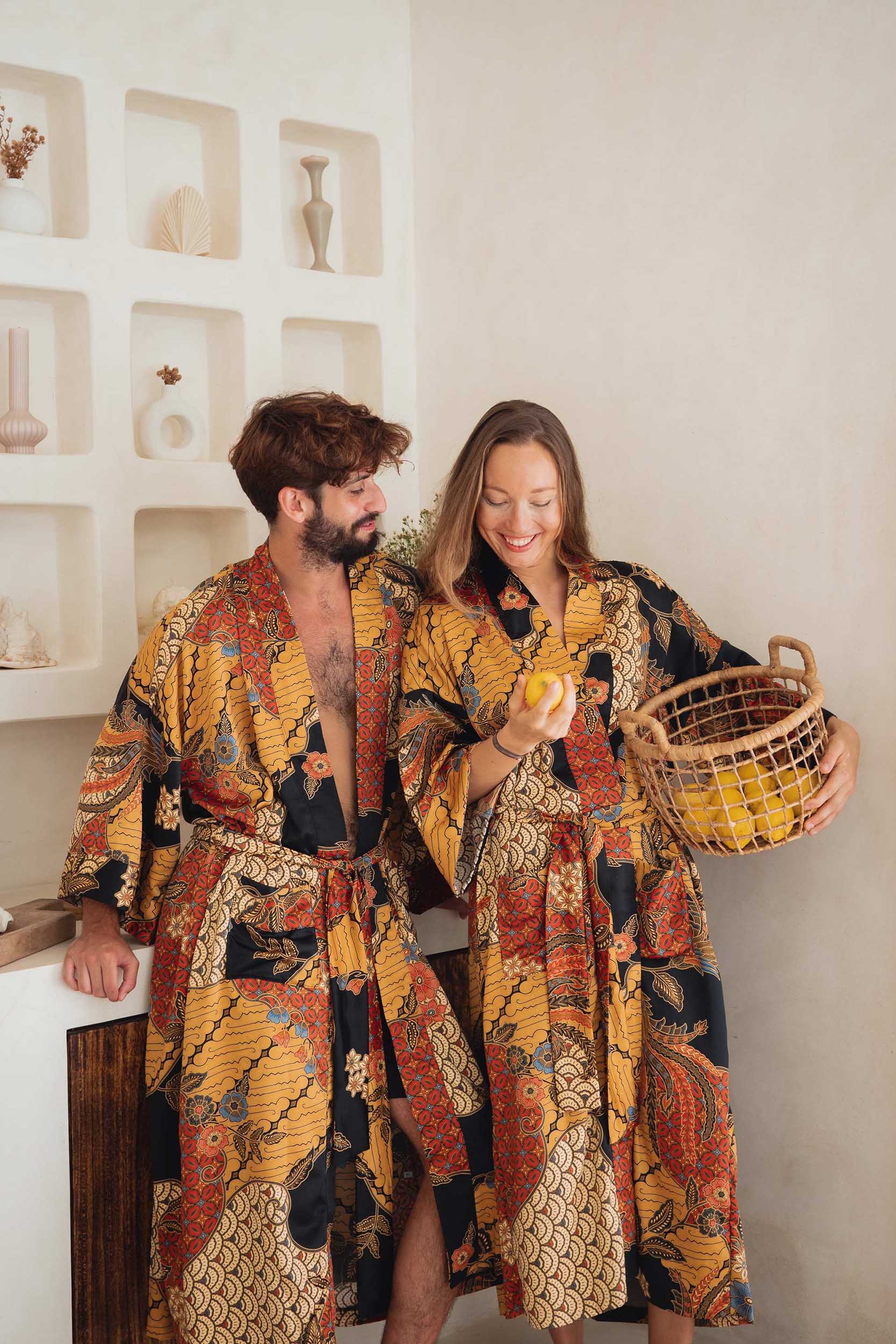 Couple wearing the Agni kimono robes – elegant satin dressing gowns with batik-inspired pattern.