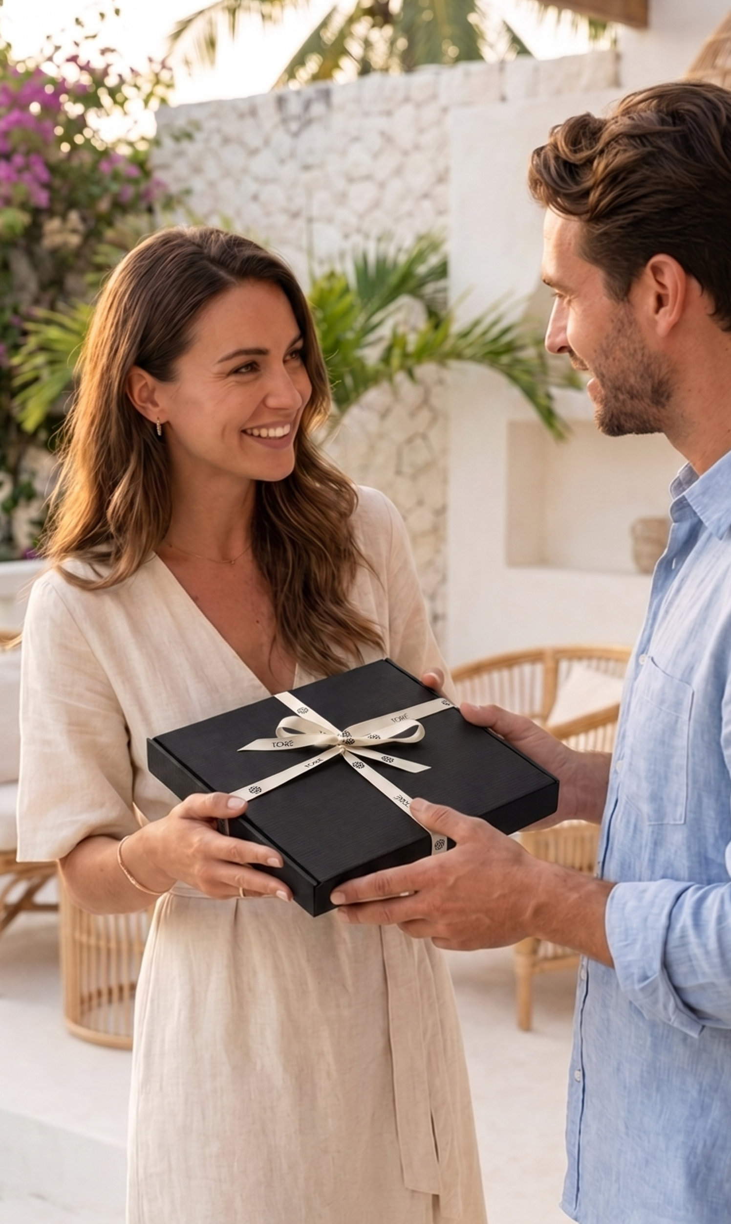 Man receiving a wrapped TORÉ gift box from a woman outdoors