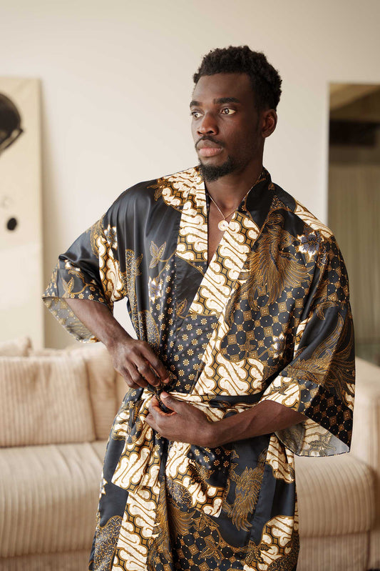 Man wearing Toré Kencana kimono robe – long black and gold satin dressing gown with traditional Javanese batik pattern.