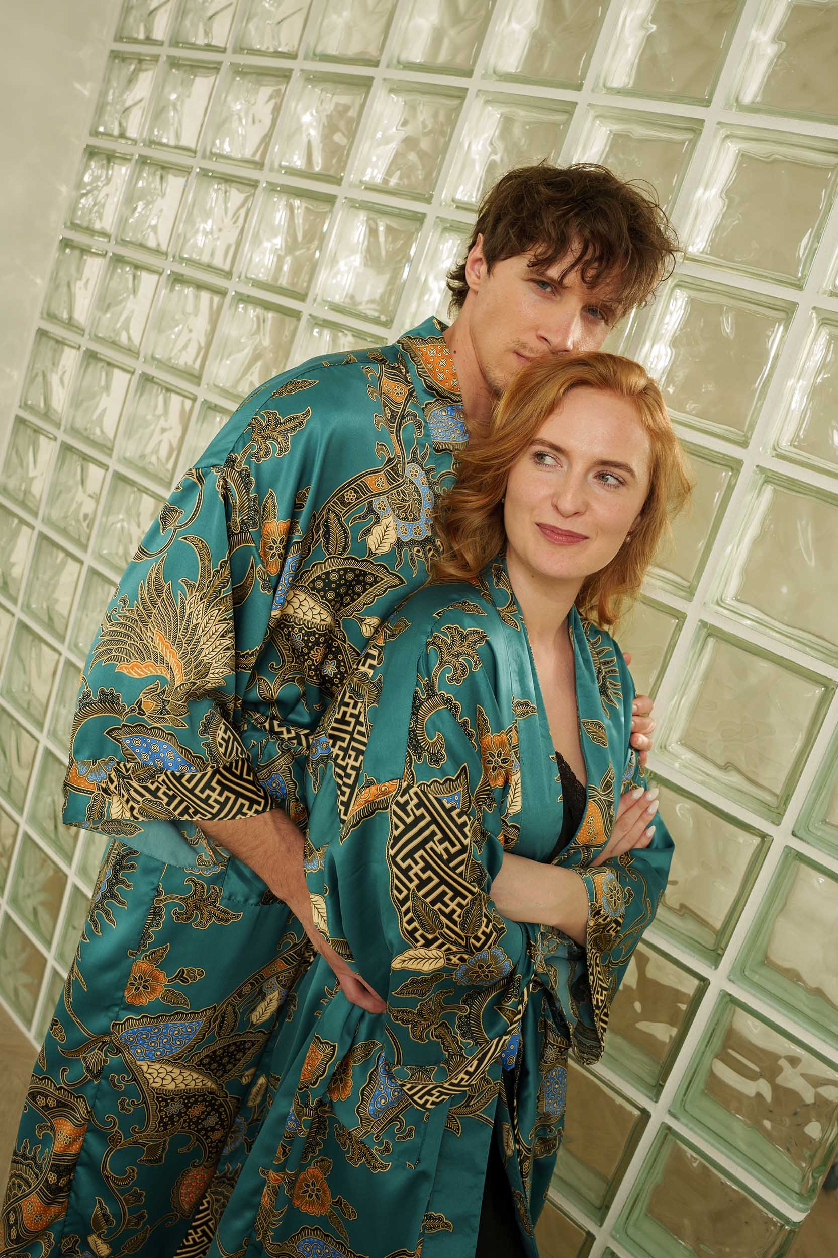 Couple wearing Lautan luxury kimono robes – teal satin long dressing gowns with ocean-inspired batik motifs.