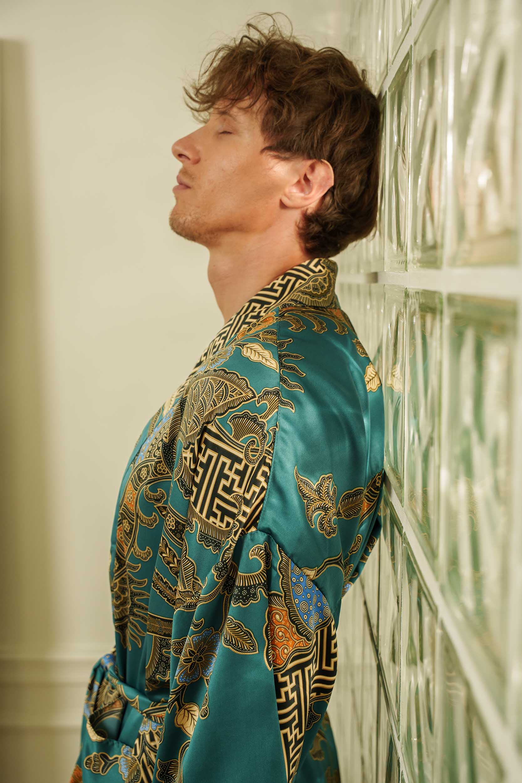 Close-up of Lautan robe fabric – teal satin with intricate gold batik print.