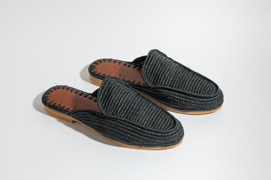 Pair of black  raffia woven slippers with brown soles on a white background