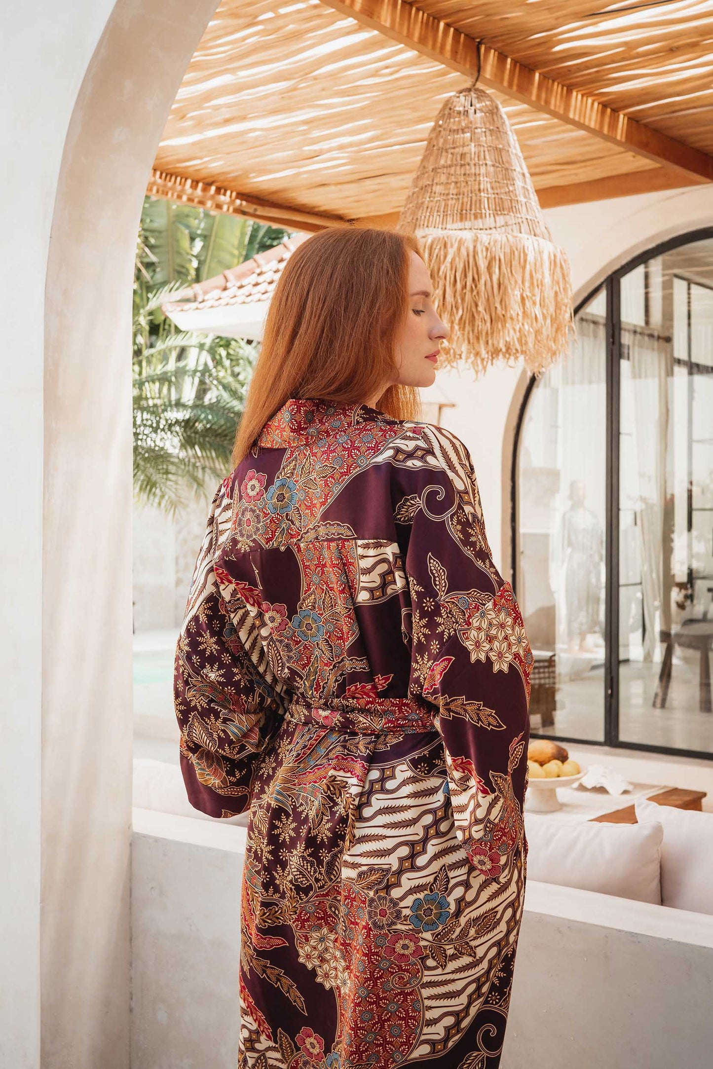 Back view of Toré Ratna robe – elegant women’s kimono in burgundy satin with soft golden pattern.