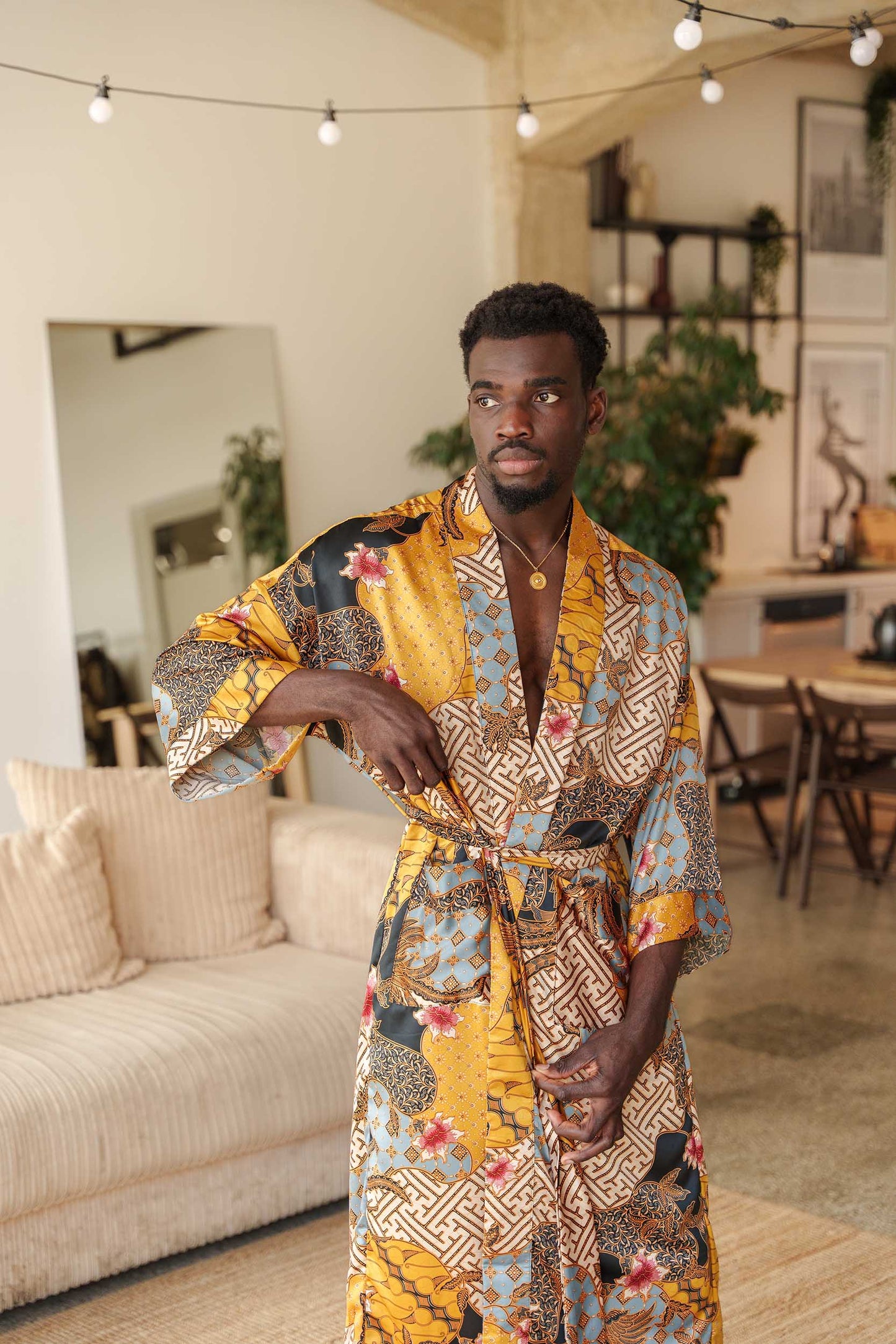 Man wearing Toré Sorga kimono robe – long yellow and blue satin dressing gown with Indonesian batik motifs.