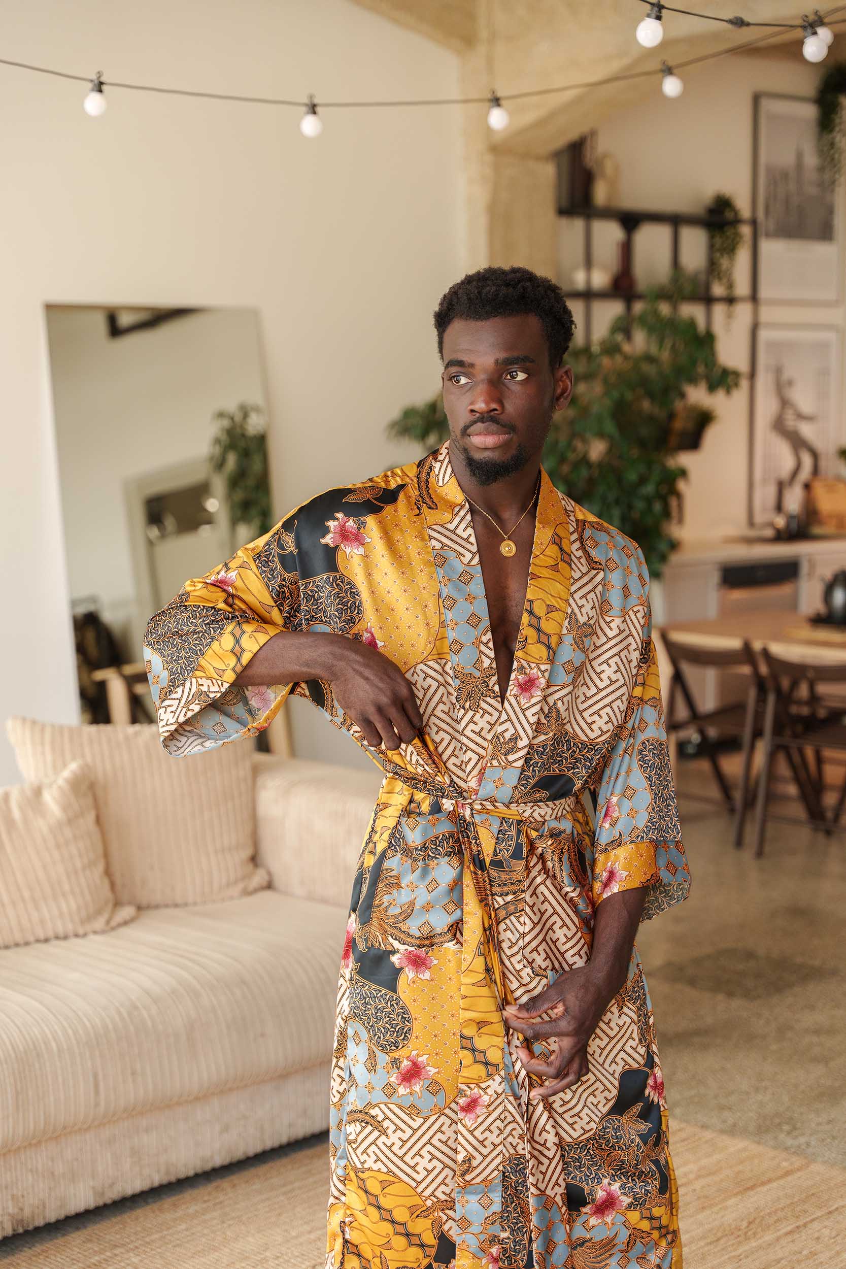 Man wearing Toré Sorga kimono robe – long yellow and blue satin dressing gown with Indonesian batik motifs.