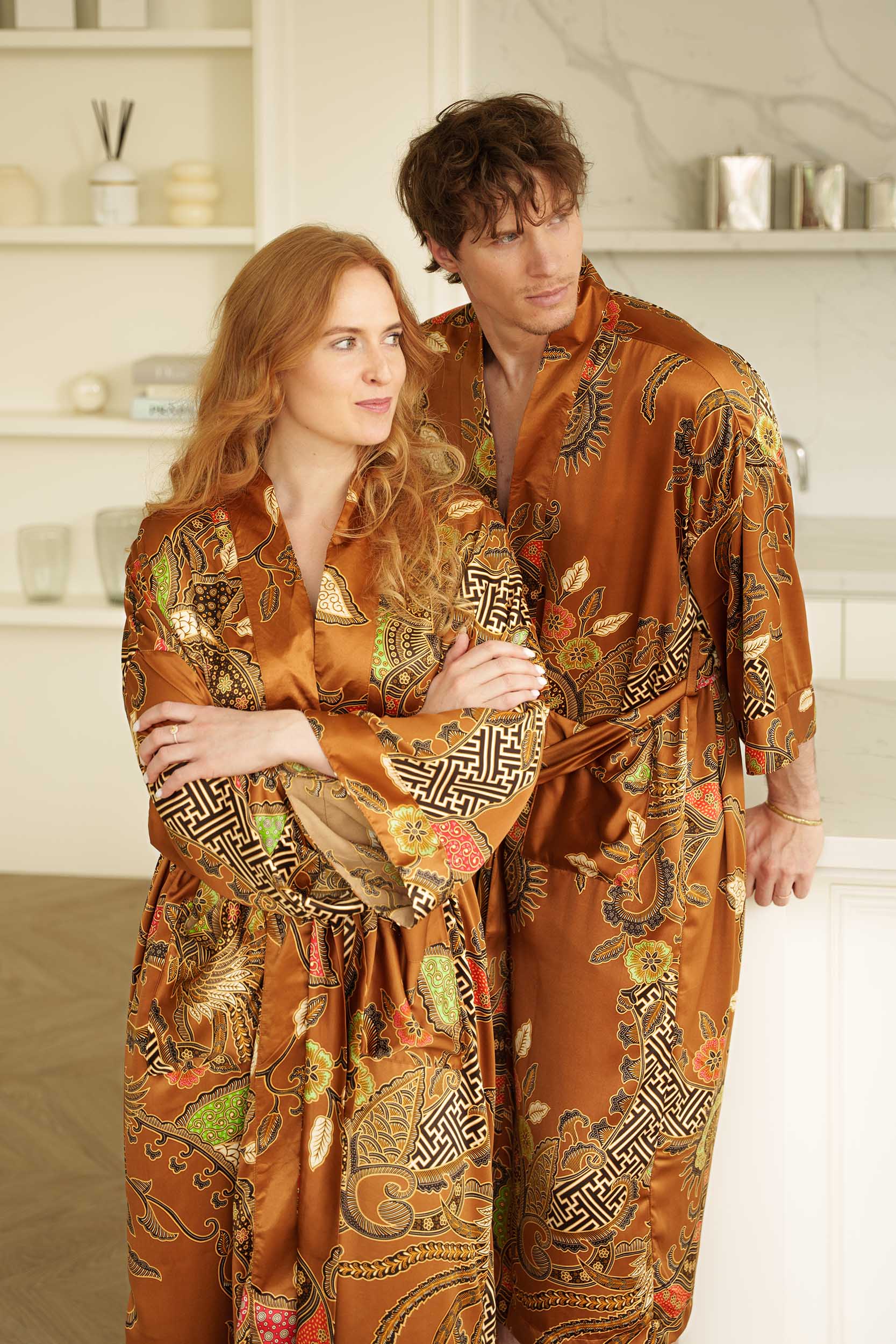 Couple wearing Surya orange-golden long kimono robes - luxury satin dressing gowns.
