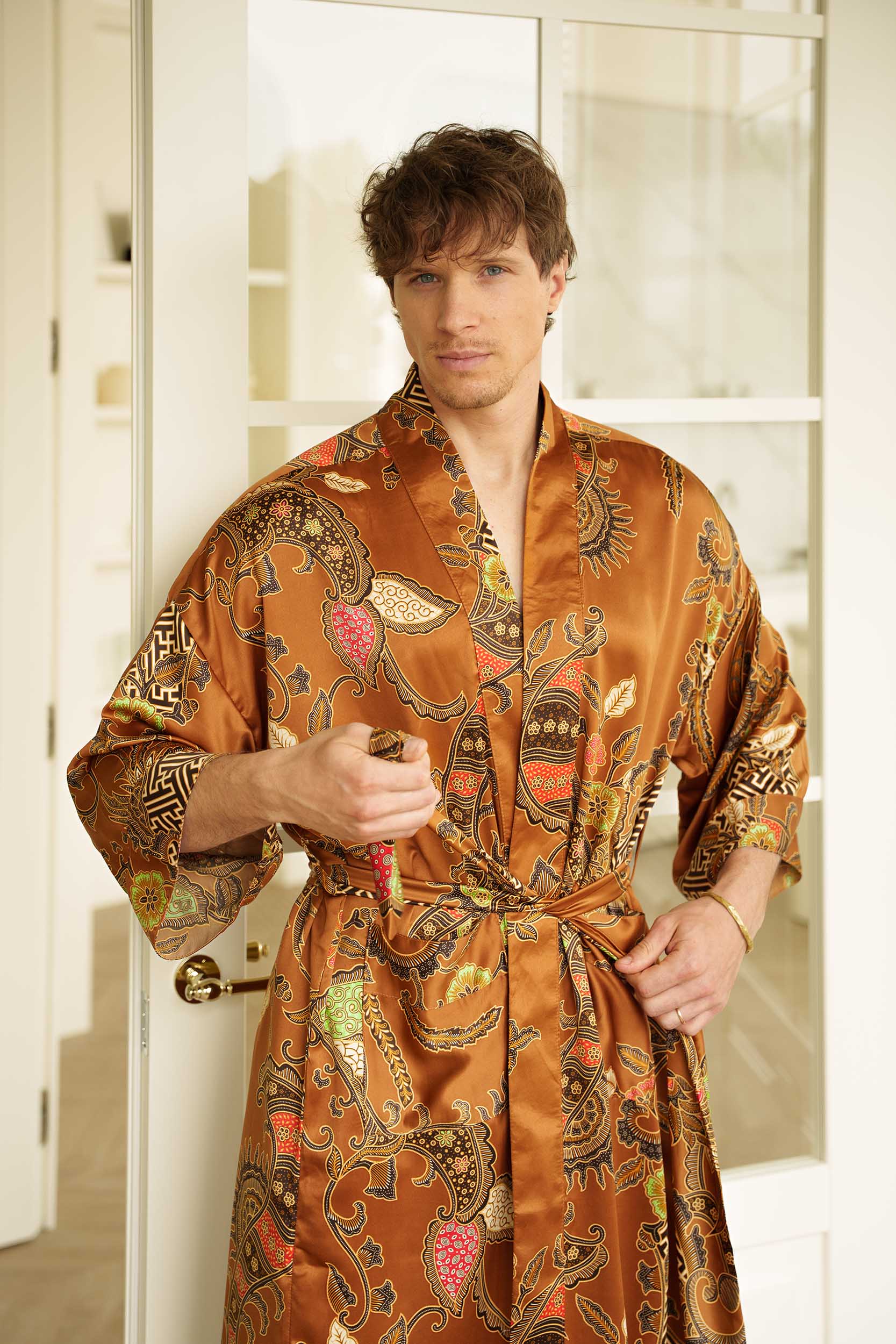 Man wearing Surya golden-orange dressing gown kimono and closing a belt.