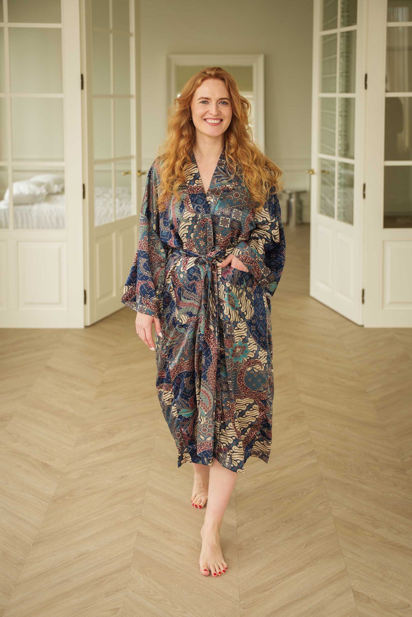 Woman wearing Toré Angkasa kimono robe – navy blue long satin dressing gown with celestial batik pattern handmade in Bali.
