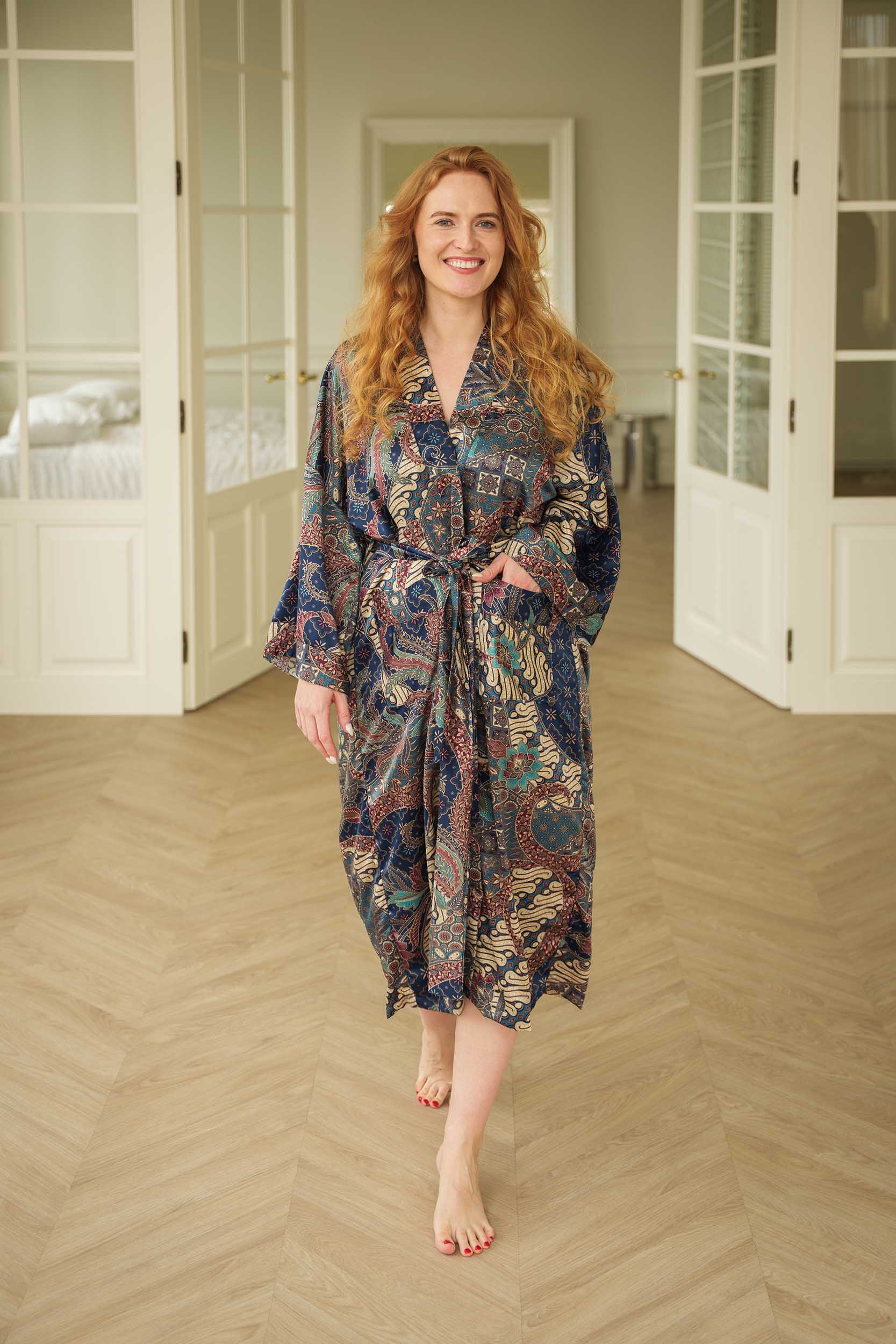 Woman wearing Toré Angkasa kimono robe – navy blue long satin dressing gown with celestial batik pattern handmade in Bali.