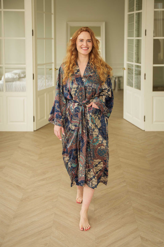 Woman wearing Toré Angkasa kimono robe – navy blue long satin dressing gown with celestial batik pattern handmade in Bali.