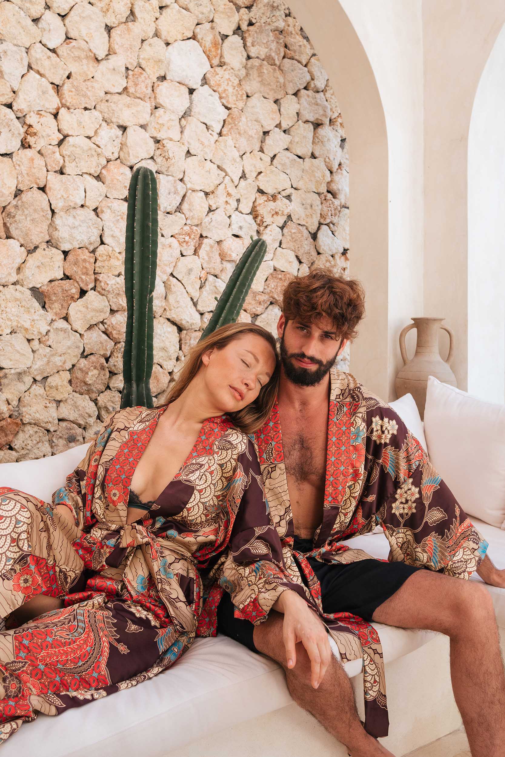 Couple wearing matching Toré Bara kimono robes – red and beige satin loungewear set.