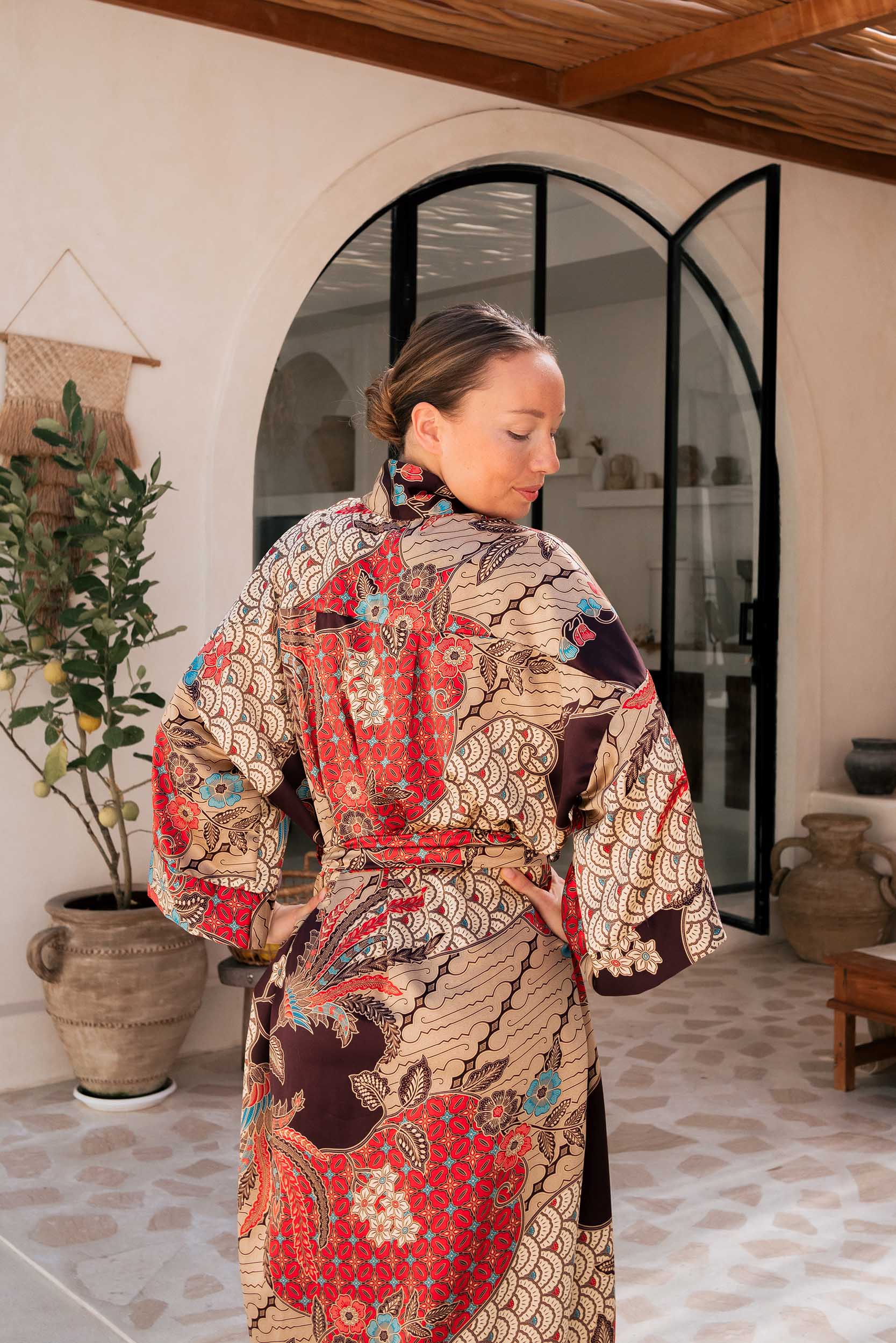 Close-up of Toré Bara fabric – smooth satin with detailed red batik pattern.