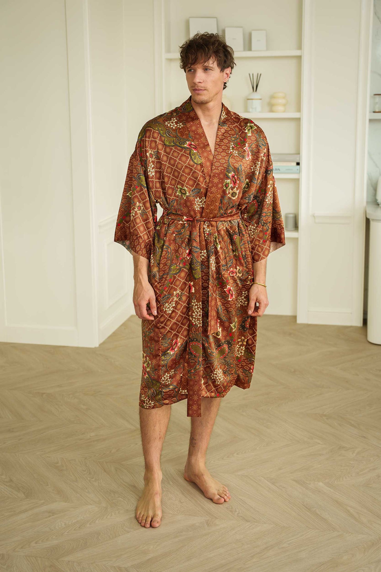 Man wearing Toré Bumi kimono robe – long satin dressing gown in brown and olive batik pattern handmade in Bali.