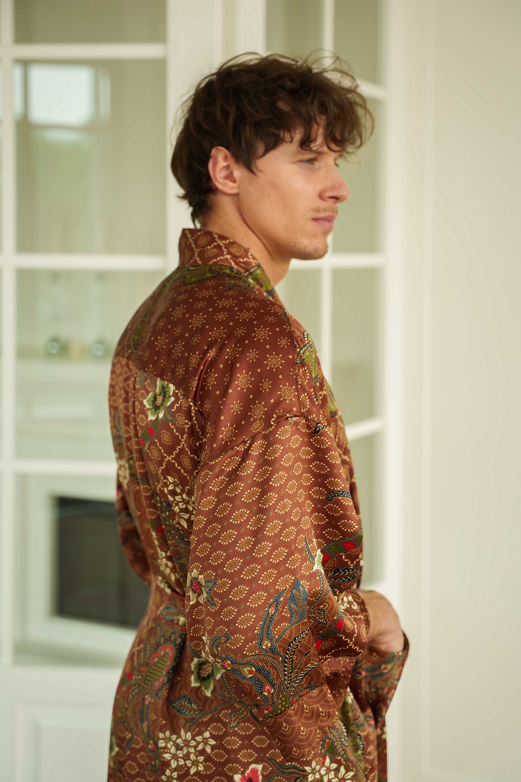 Side view of man in Toré Bumi kimono robe – long satin brown dressing gown with pockets.
