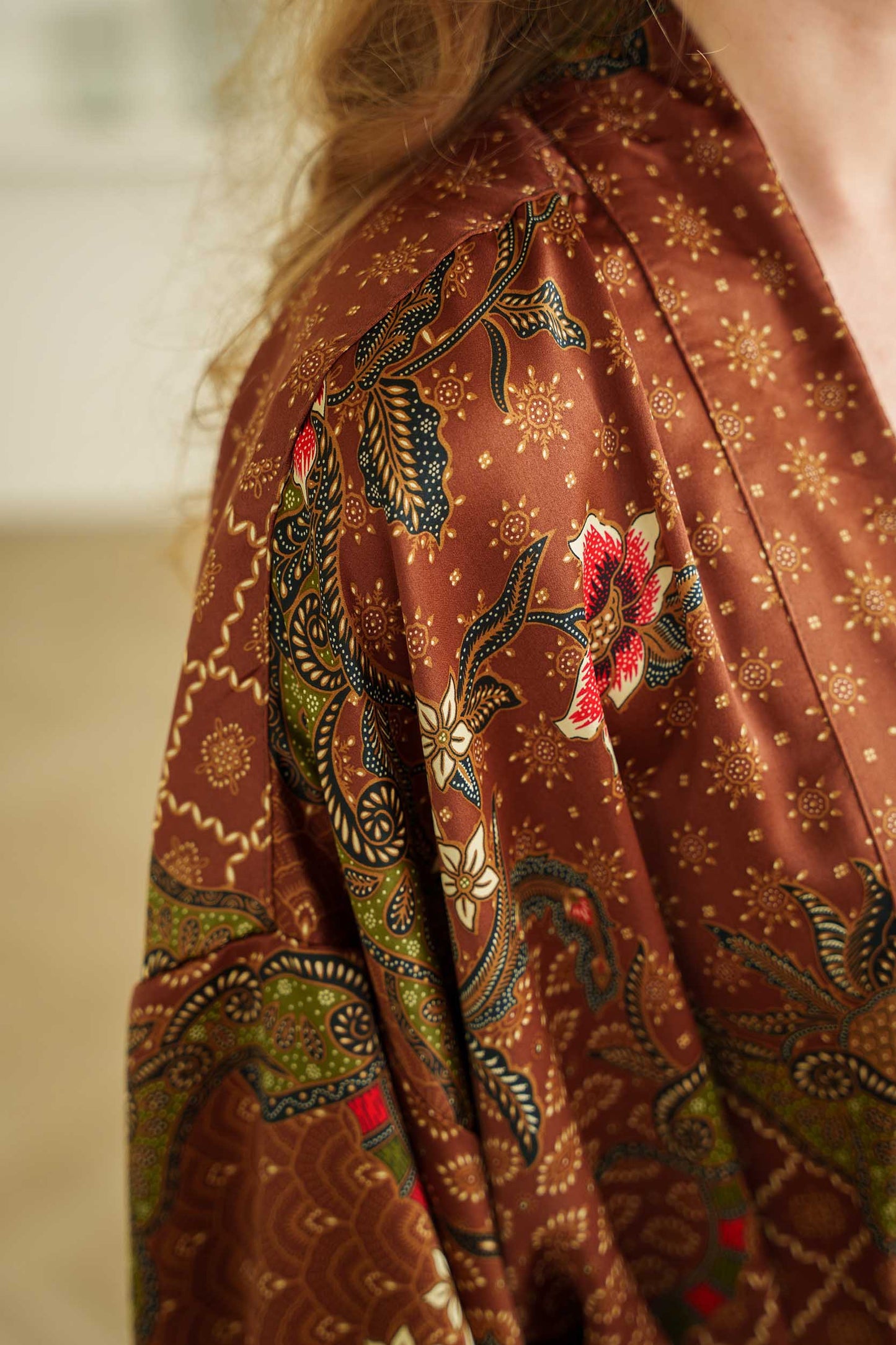 Close-up of Toré Bumi kimono robe fabric – silky satin texture with floral batik print.