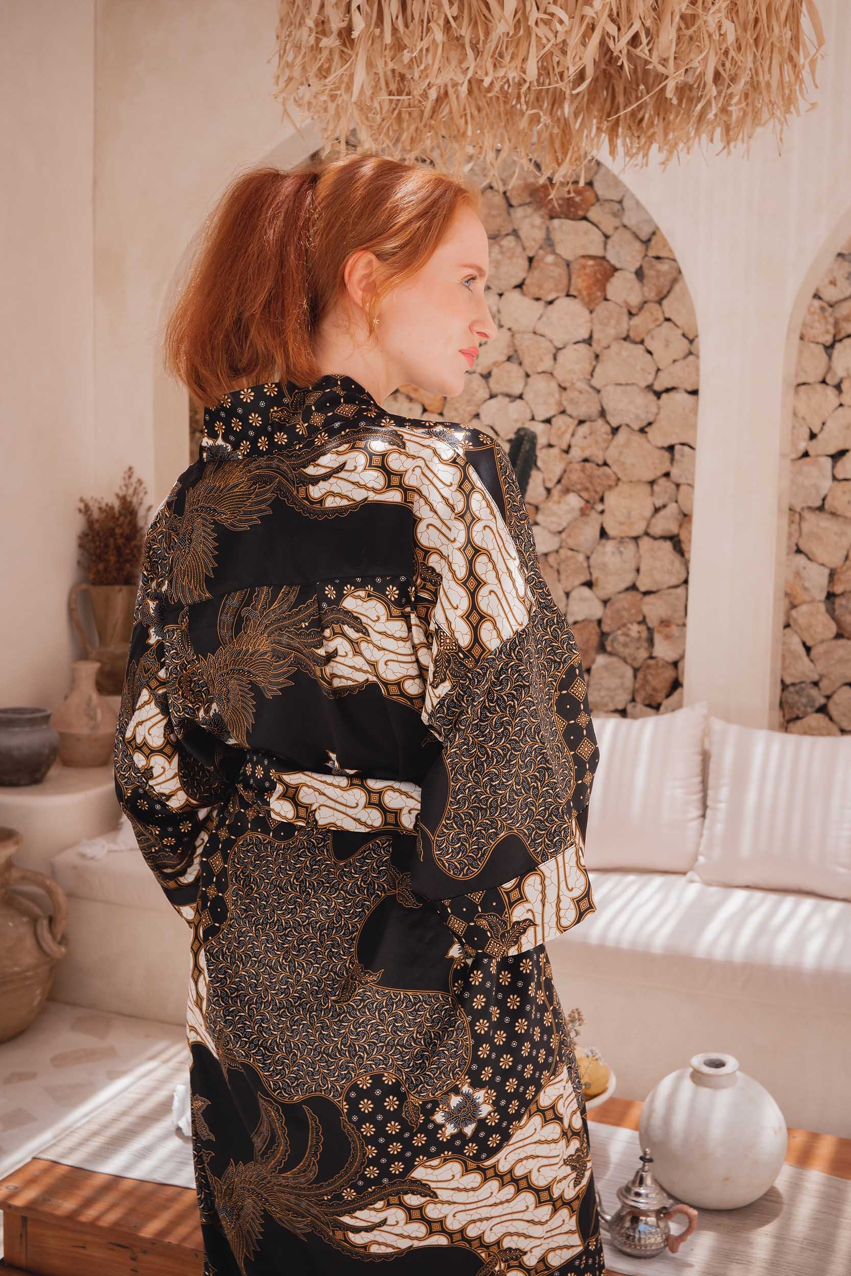Back view of Toré Kencana women’s robe – black satin kimono with golden details and soft drape.