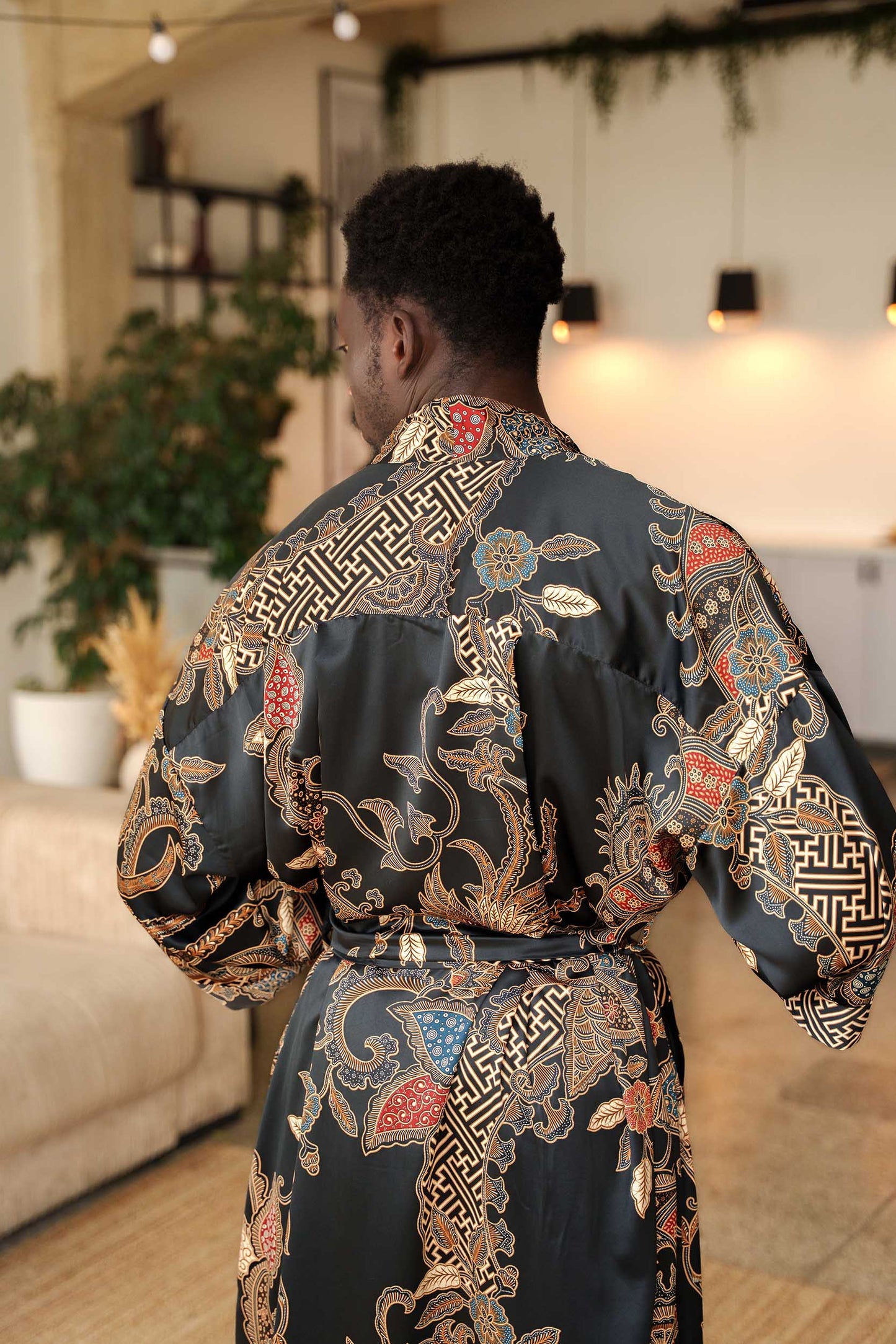 Back view of Toré Malam robe – men’s black satin kimono with elegant gold batik motifs.