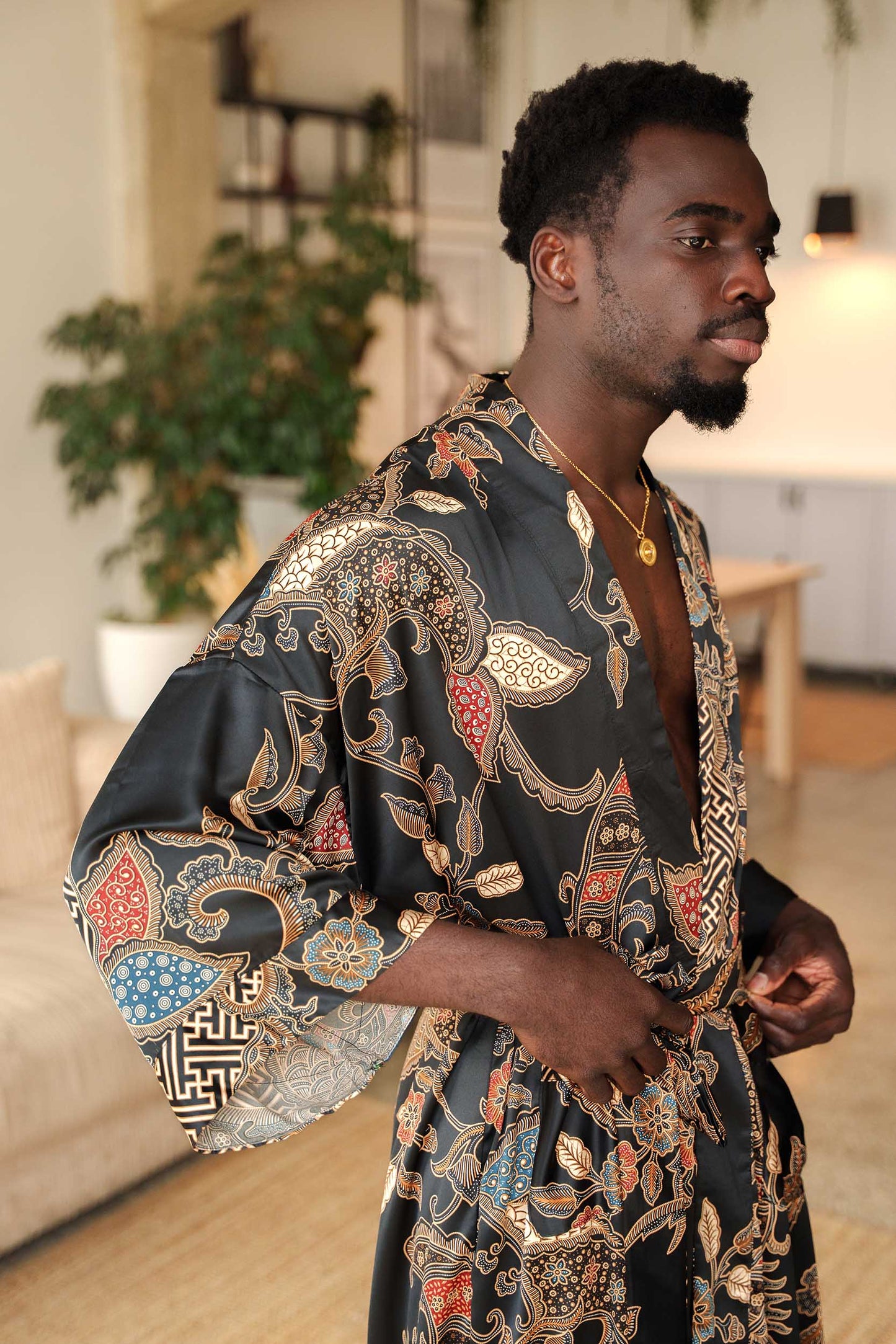 Close-up of Toré Malam robe fabric – smooth satin with red and gold batik-inspired detailing.