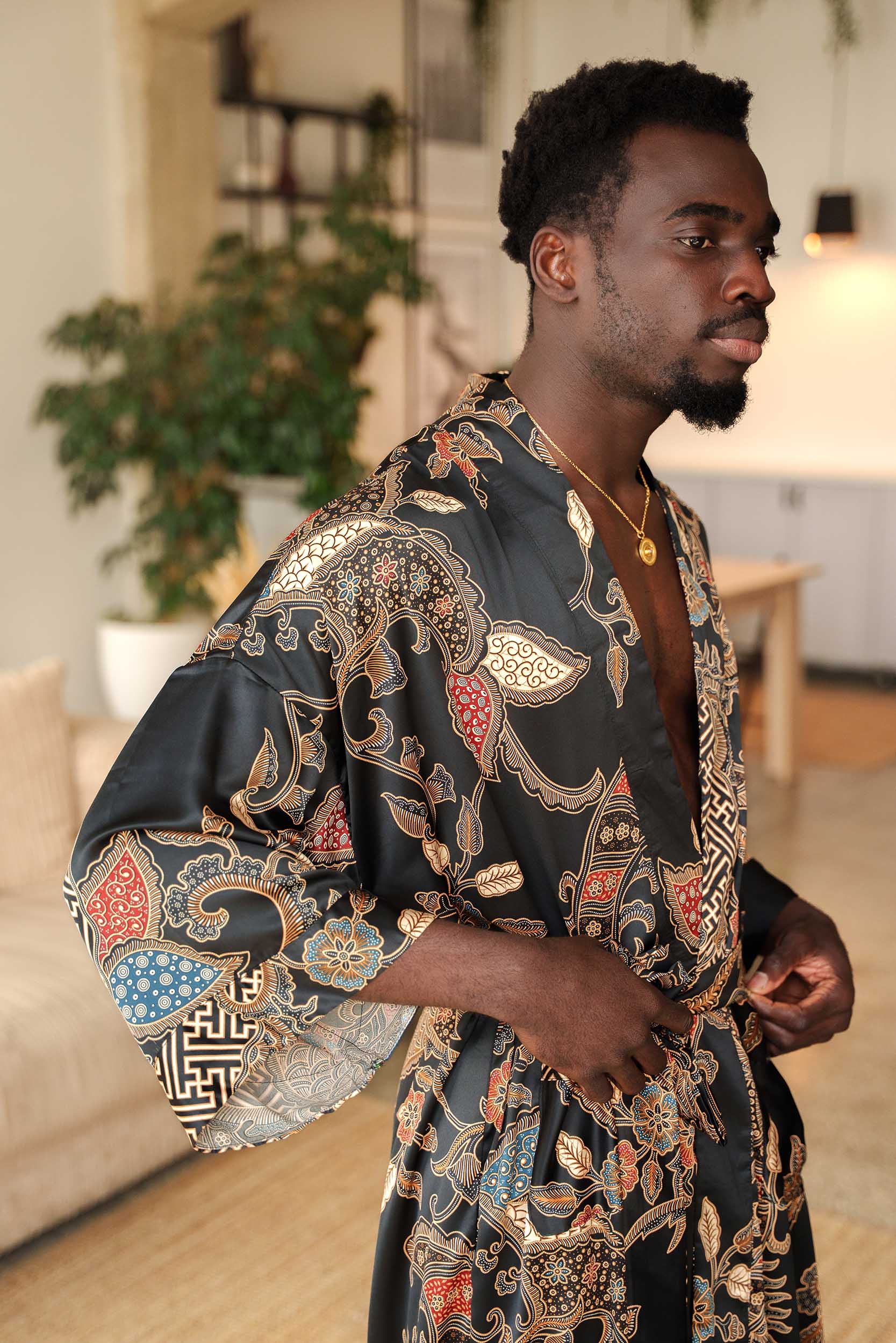 Close-up of Toré Malam robe fabric – smooth satin with red and gold batik-inspired detailing.