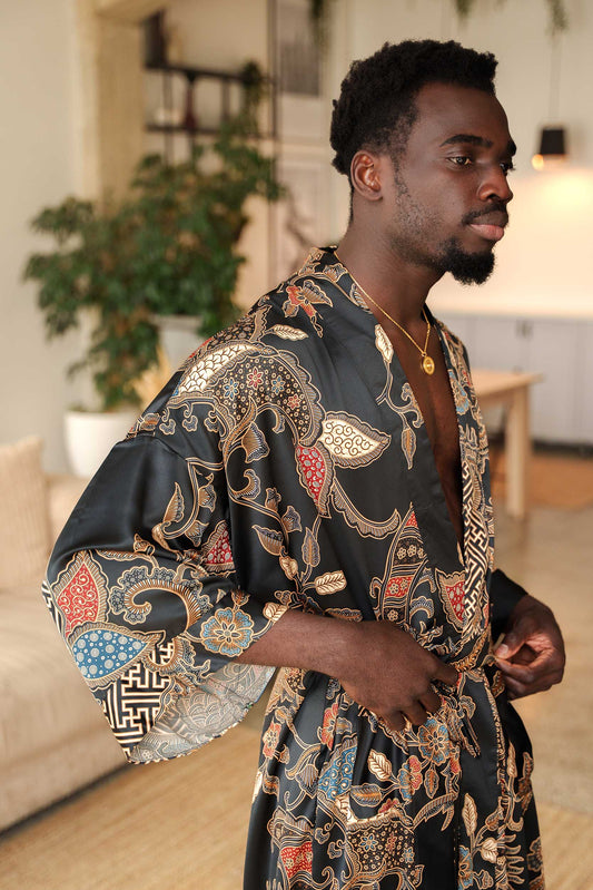Close-up of Toré Malam robe fabric – smooth satin with red and gold batik-inspired detailing.