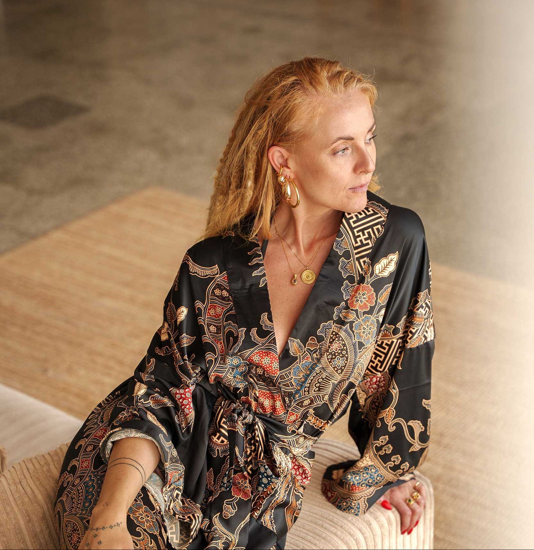 Woman wearing women's black kimono robe and lounging on a sofa