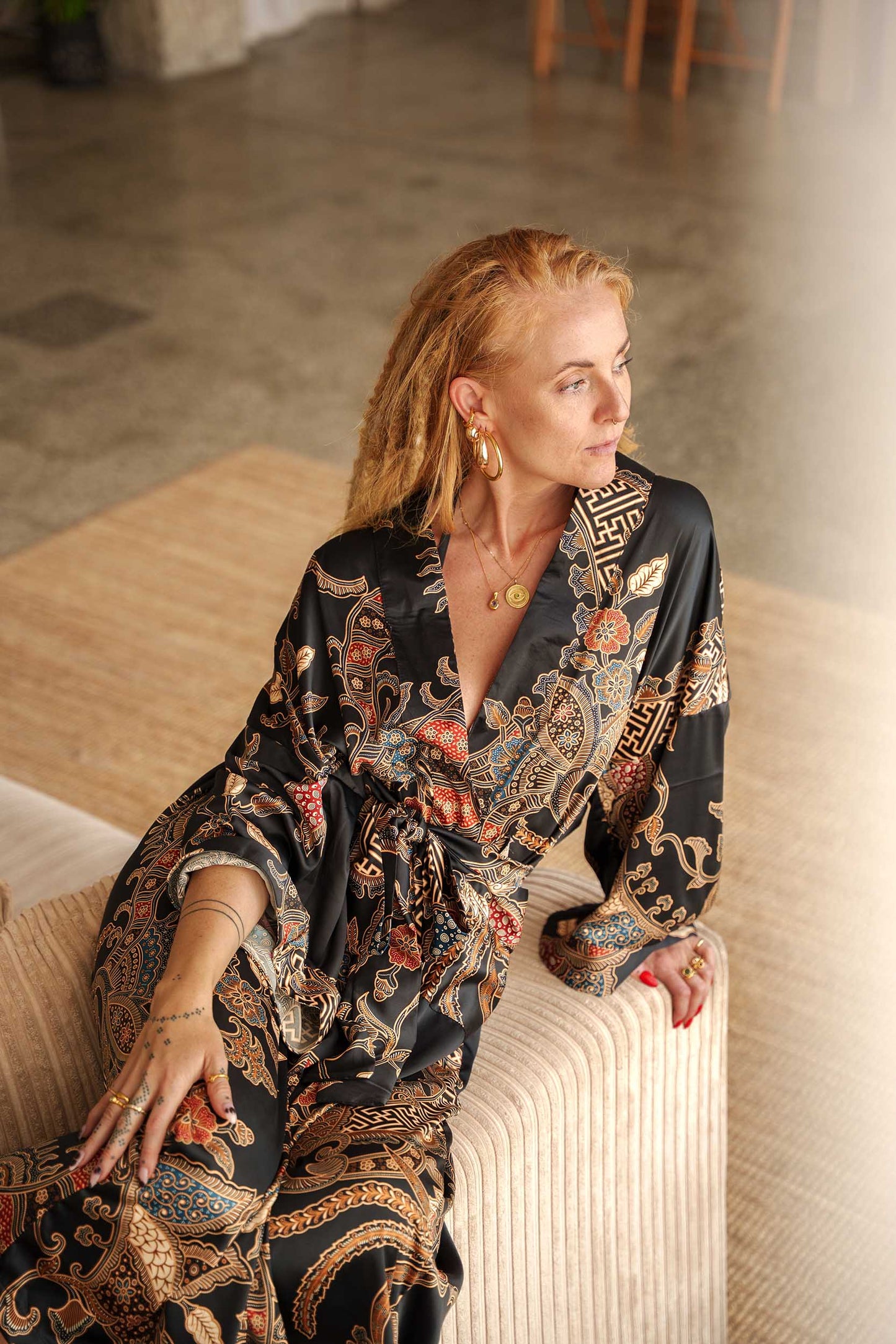 Side view of Toré Malam women’s kimono robe – elegant black satin robe with detailed floral batik pattern.