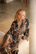 Side view of Toré Malam women’s kimono robe – elegant black satin robe with detailed floral batik pattern.