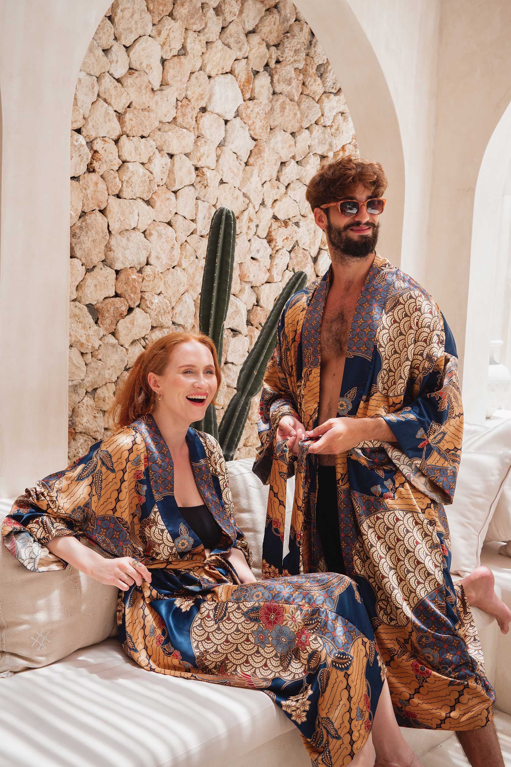 Couple wearing matching Toré Nilam kimono robes – elegant blue and gold satin dressing gowns.