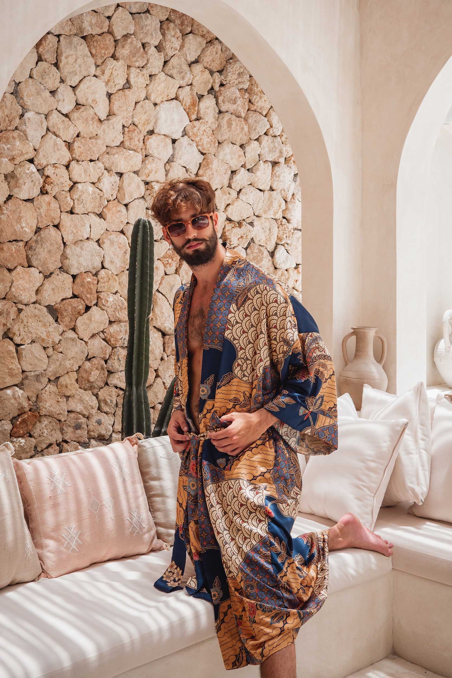 Man wearing Toré Nilam kimono robe – long blue satin dressing gown with gold batik pattern.