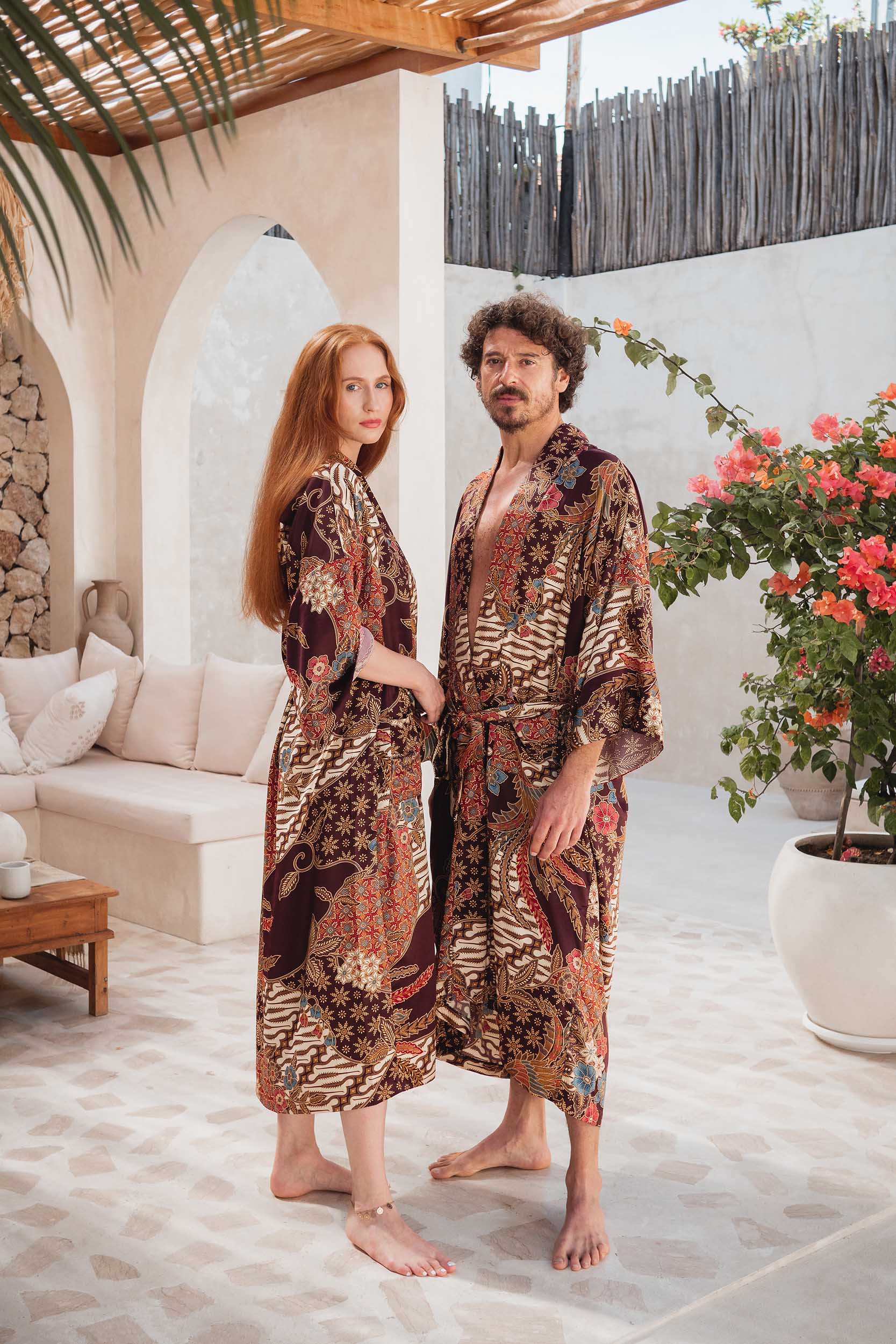 Man and woman in Toré Ratna robes – luxury matching kimono robes in deep burgundy satin inspired by Indonesian design.