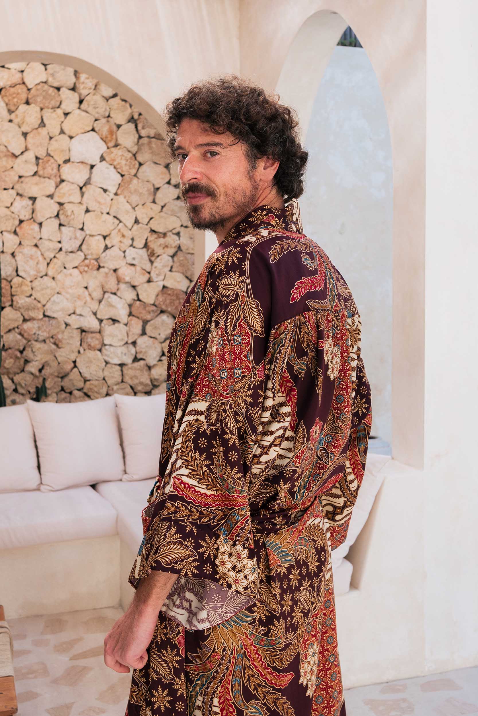 Side view of Toré Ratna men’s robe – luxury burgundy satin kimono with Indonesian-inspired golden motifs.