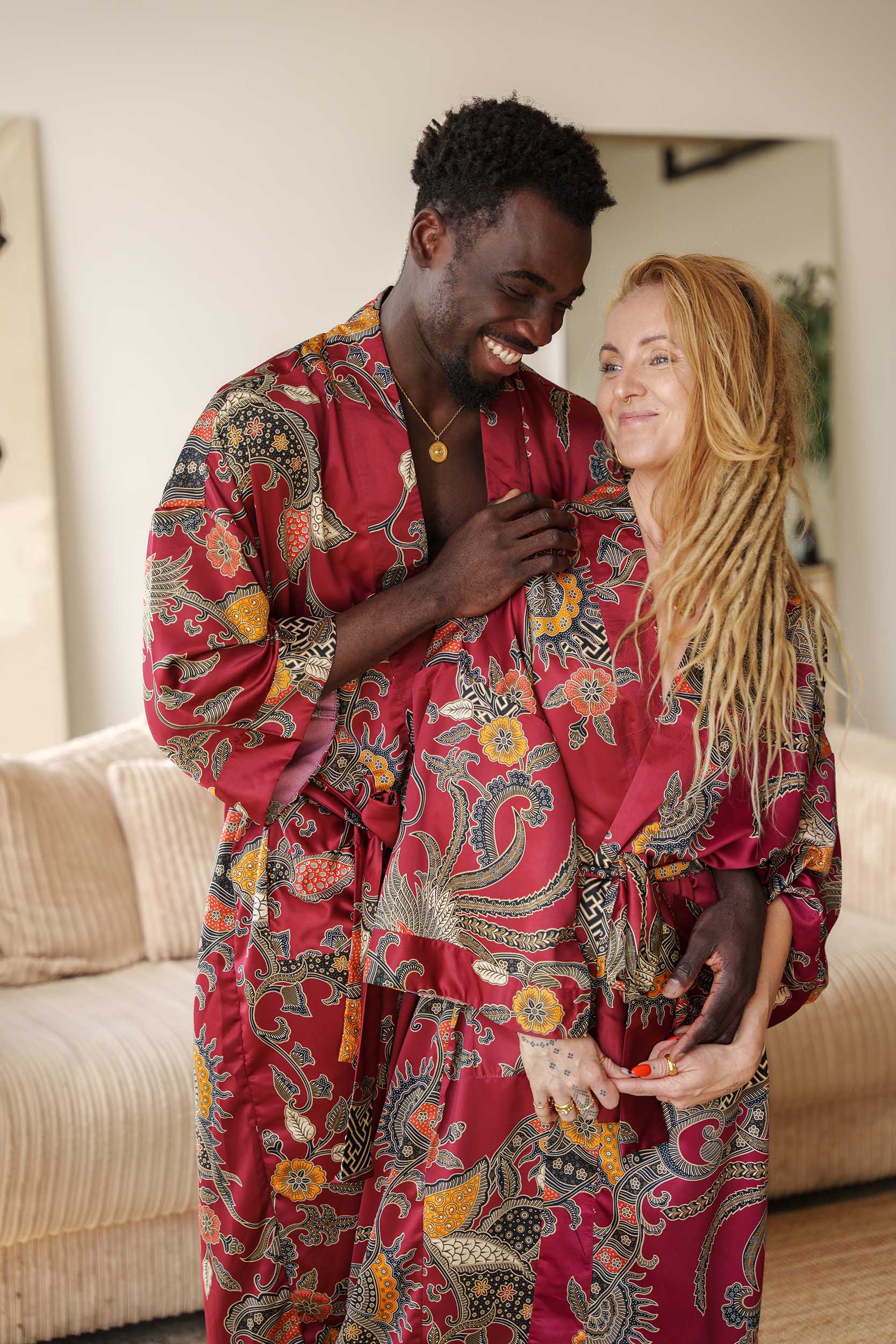Couple wearing matching Toré Sekar kimono robes – red satin dressing gowns inspired by Balinese artistry.