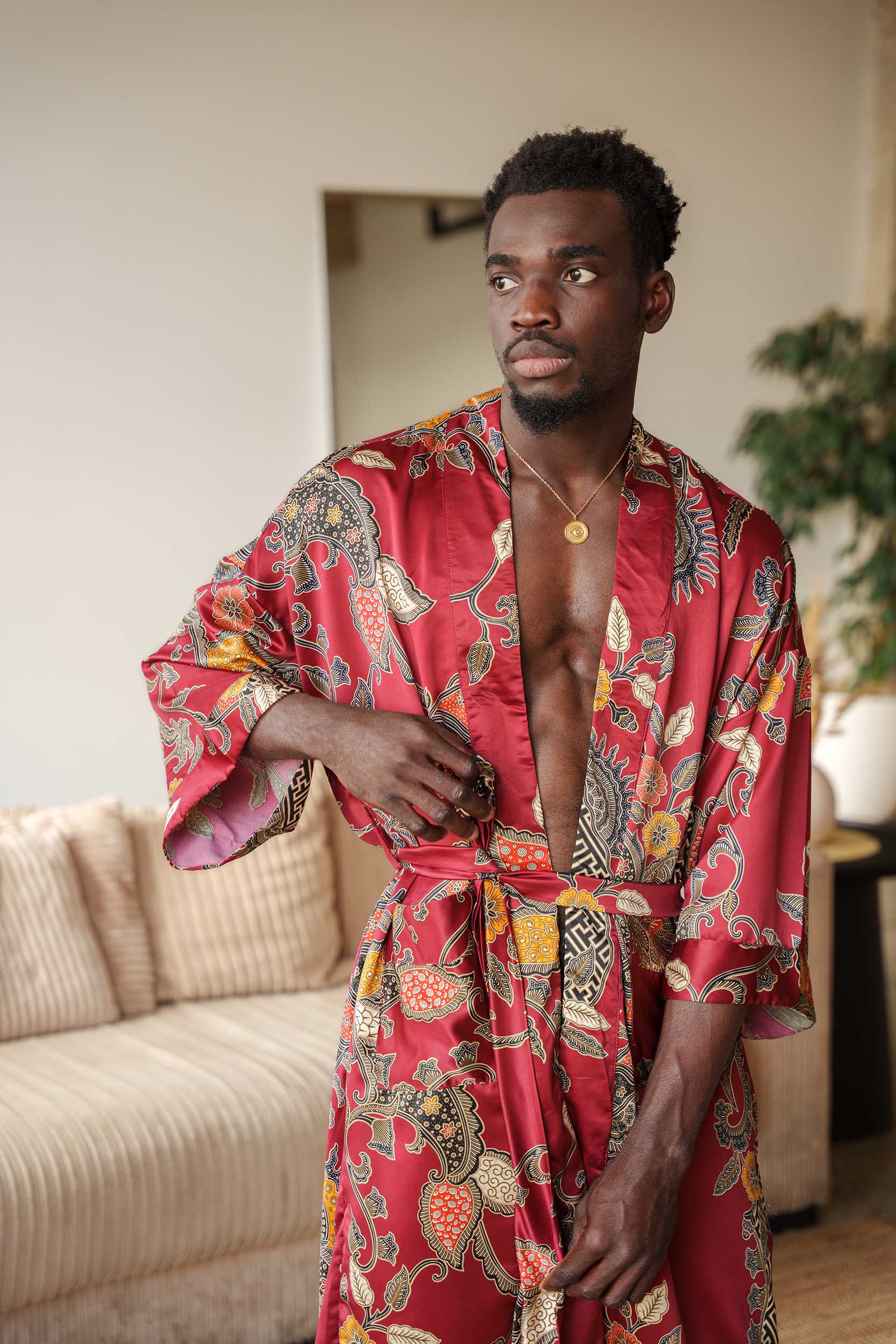 Front view of Toré Sekar men’s kimono robe – cherry-red satin robe with intricate gold batik pattern.