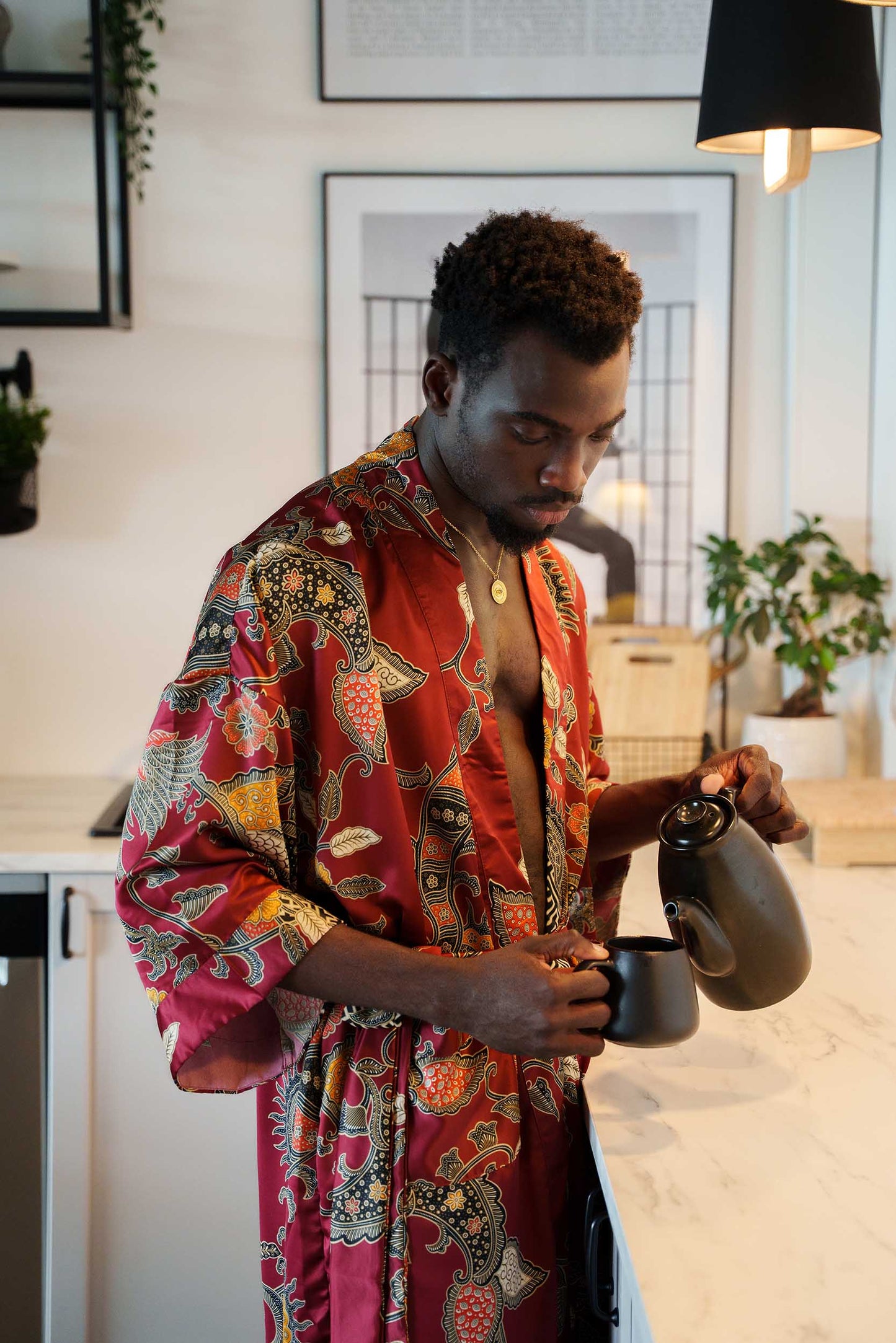 Man wearing Toré Sekar kimono robe – long red satin dressing gown pouring coffee in a cup.