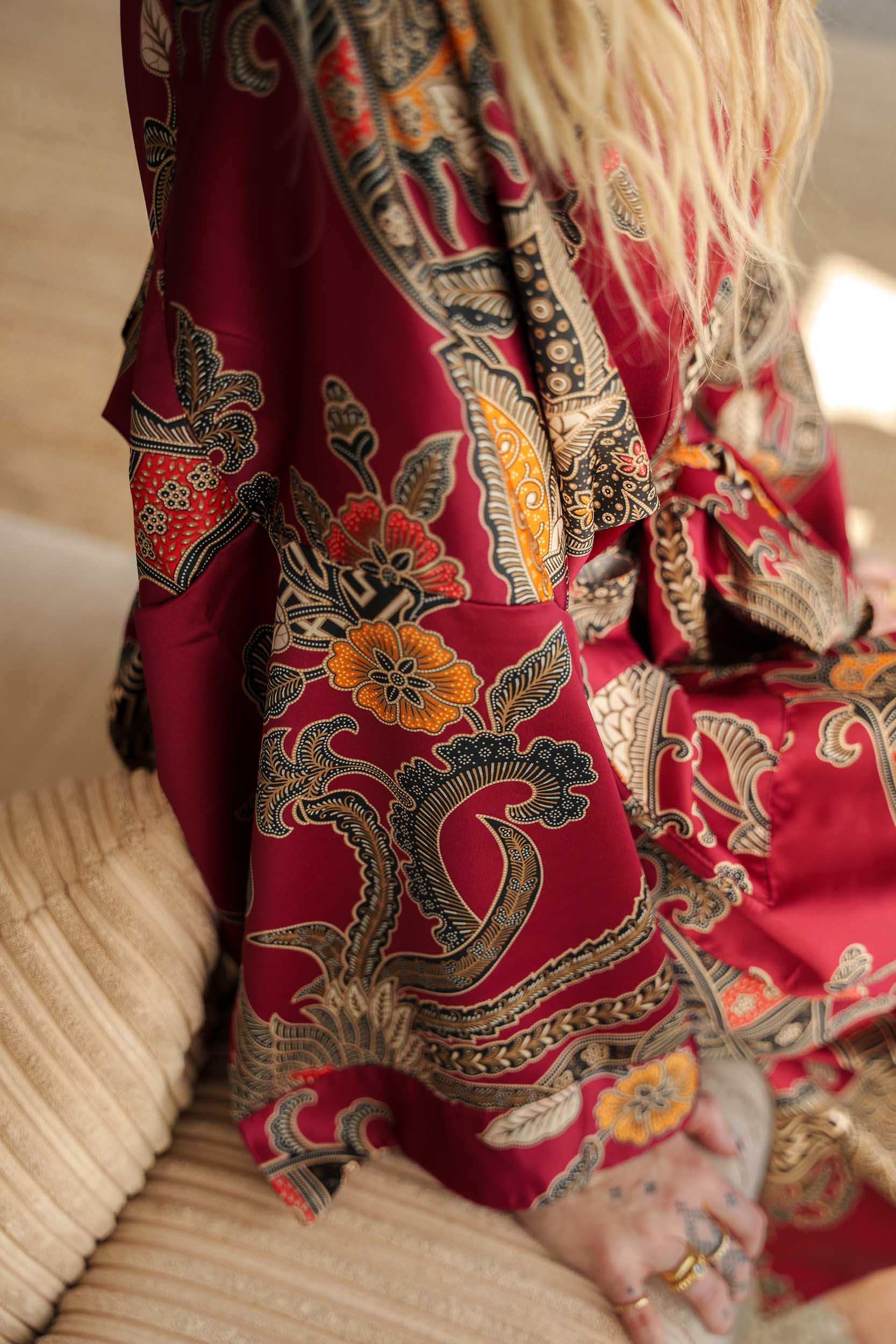 Close-up of Toré Sekar robe fabric – soft satin with delicate floral and gold batik details.