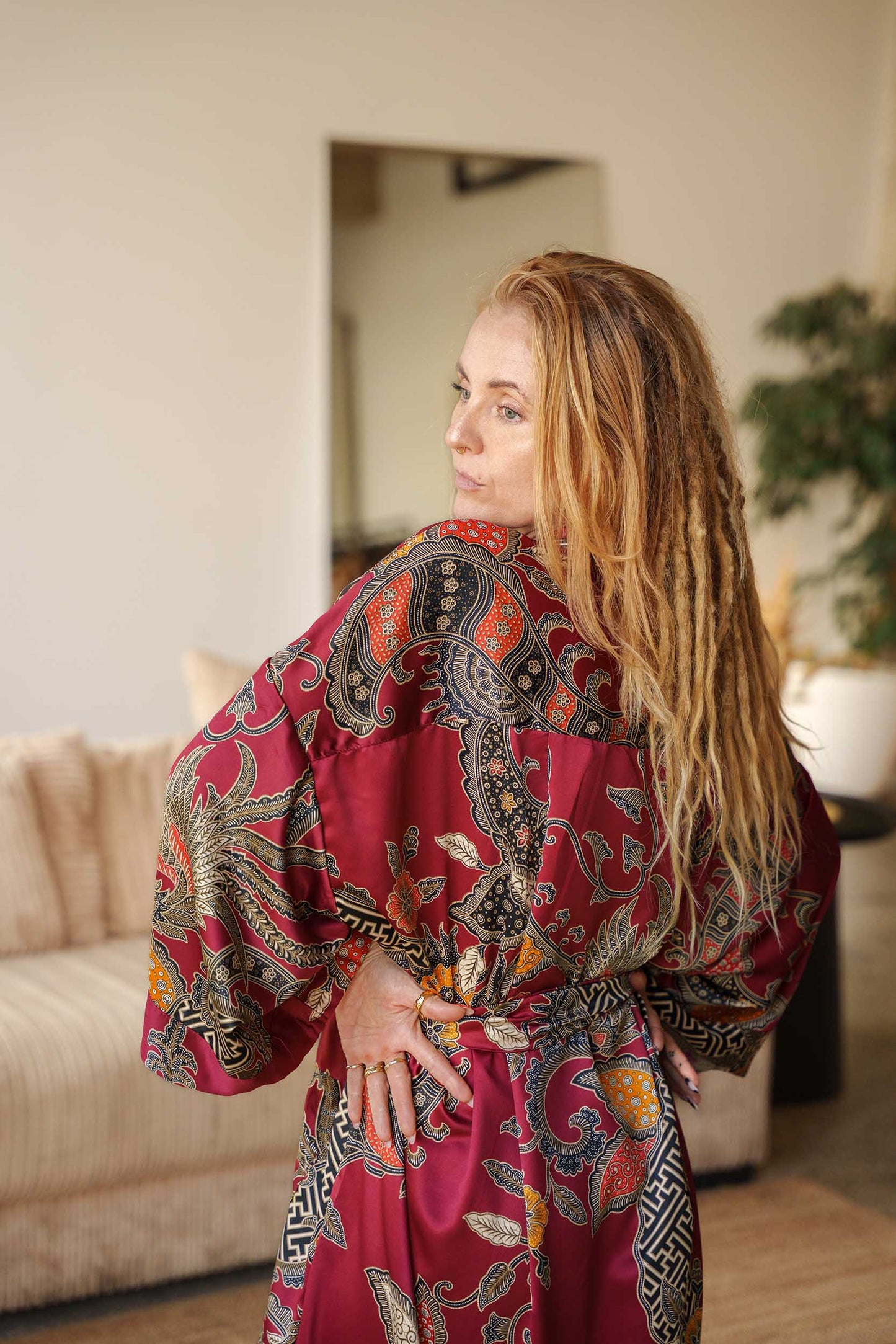 Side view of Toré Sekar women’s kimono robe – cherry-red satin robe with golden floral motifs.