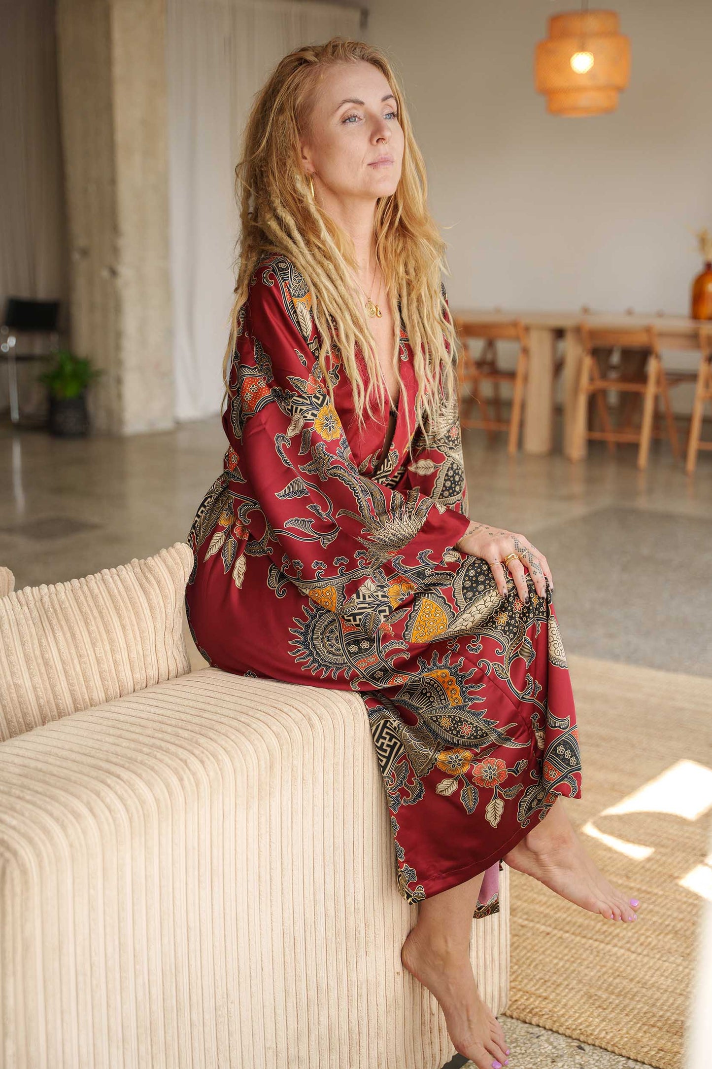 Woman wearing Toré Sekar kimono robe sitting on a coach.