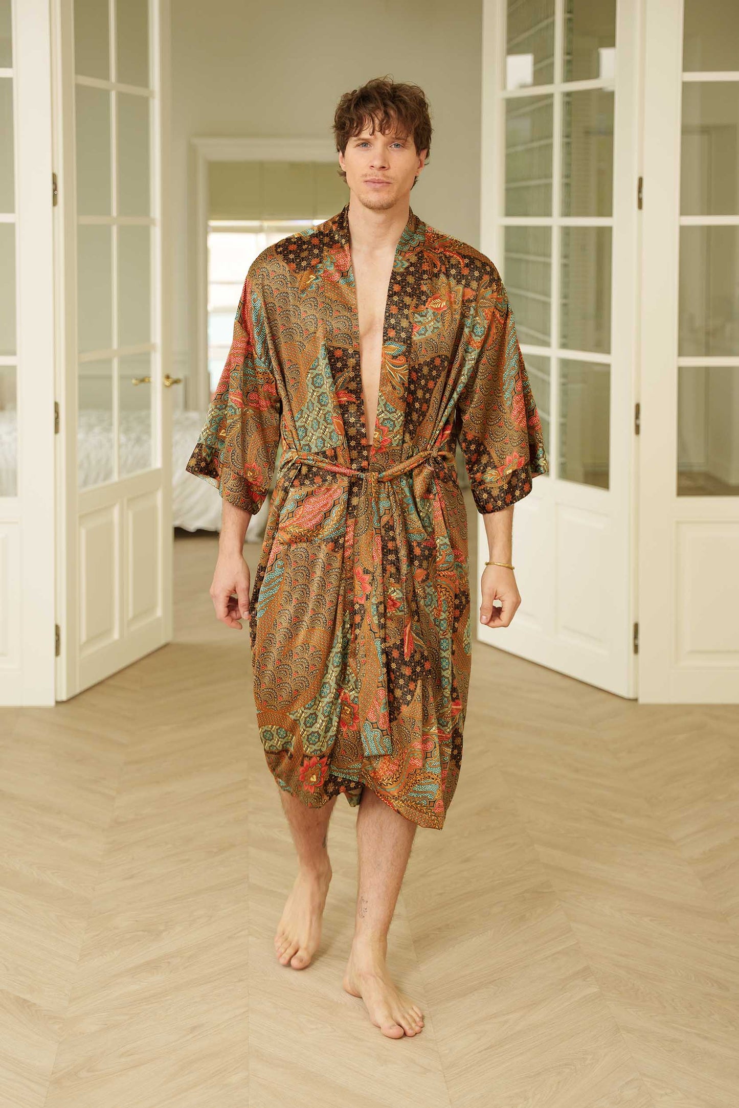 Man wearing Toré Semesta kimono robe – long satin dressing gown in black and turquoise batik pattern handmade in Bali.