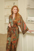 Woman wearing Toré Semesta kimono robe – long satin dressing gown in turquoise and coral batik pattern handmade in Bali.