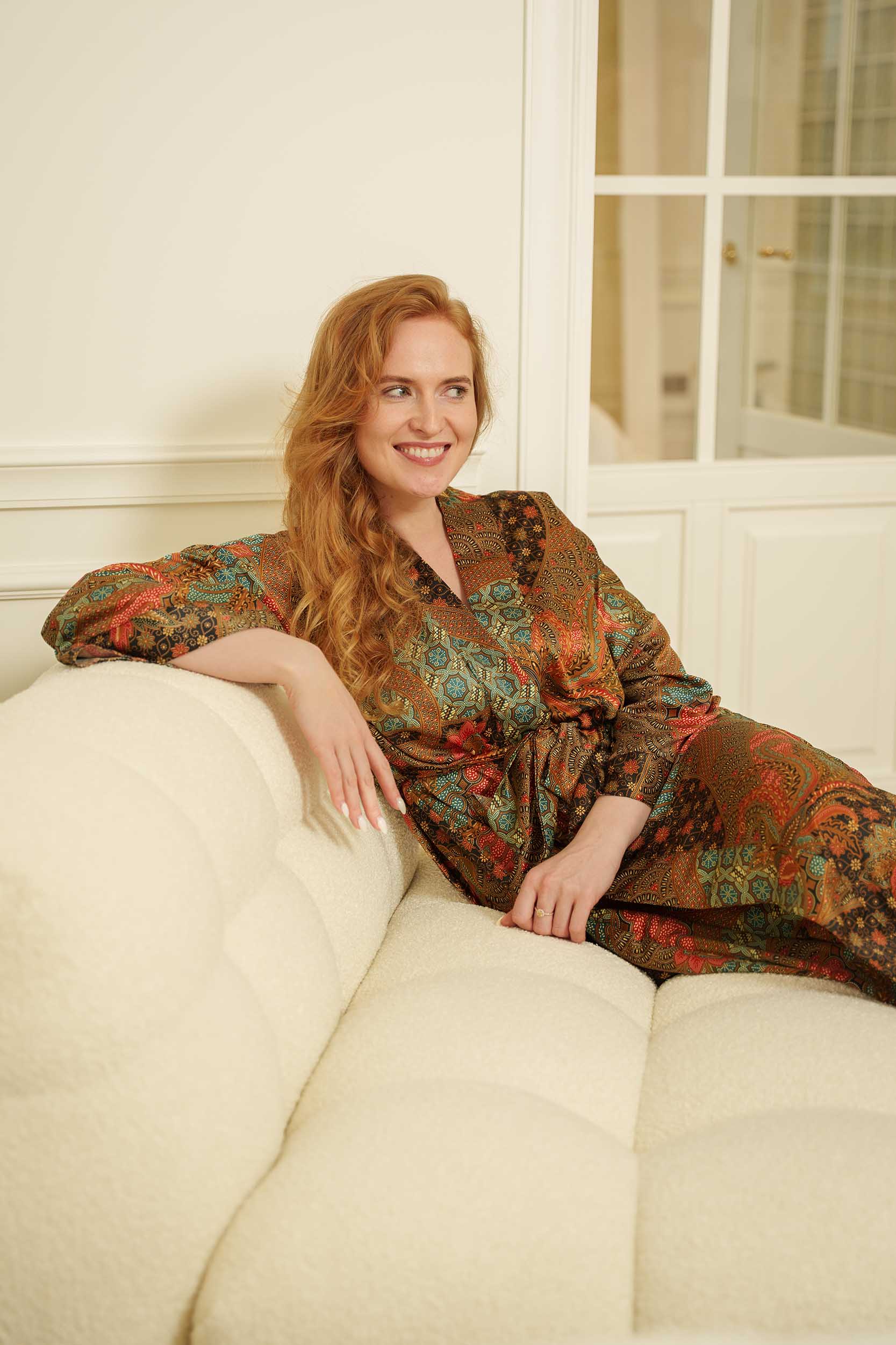 Woman wearing Semesta batik long dressing gown and sitting on the coach.
