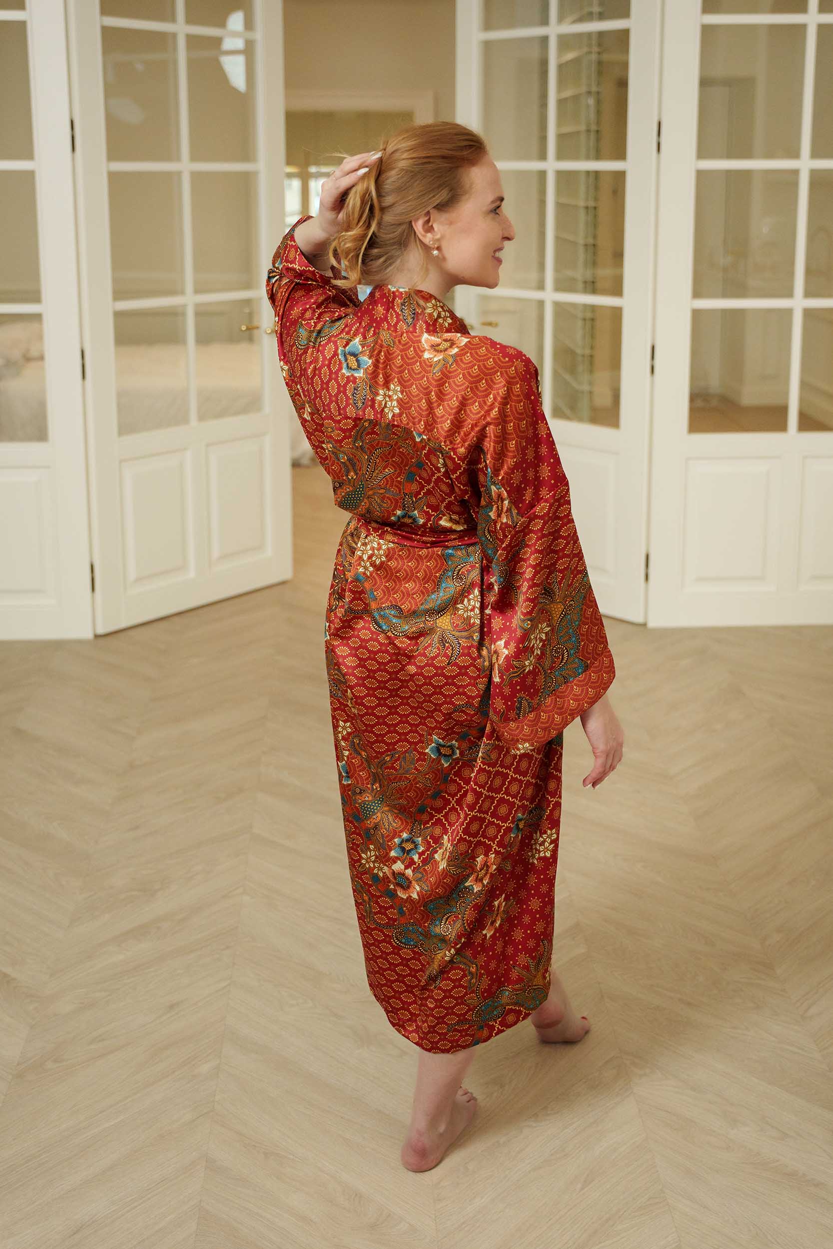 Back view of Toré Senja kimono robe – soft red satin fabric with intricate gold and teal batik details.