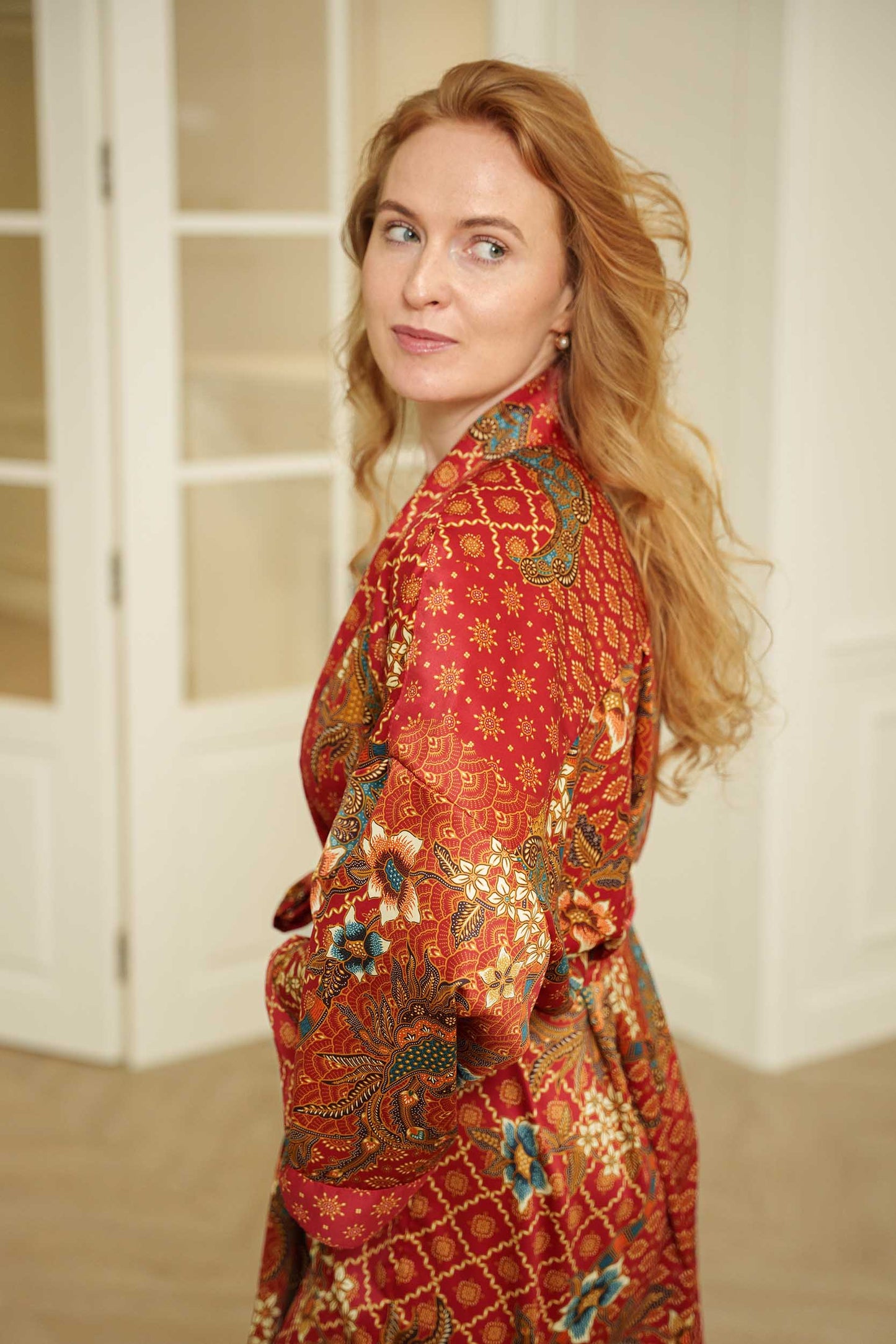 Side view of Toré Senja women’s kimono robe – elegant red satin robe with Indonesian-inspired pattern.