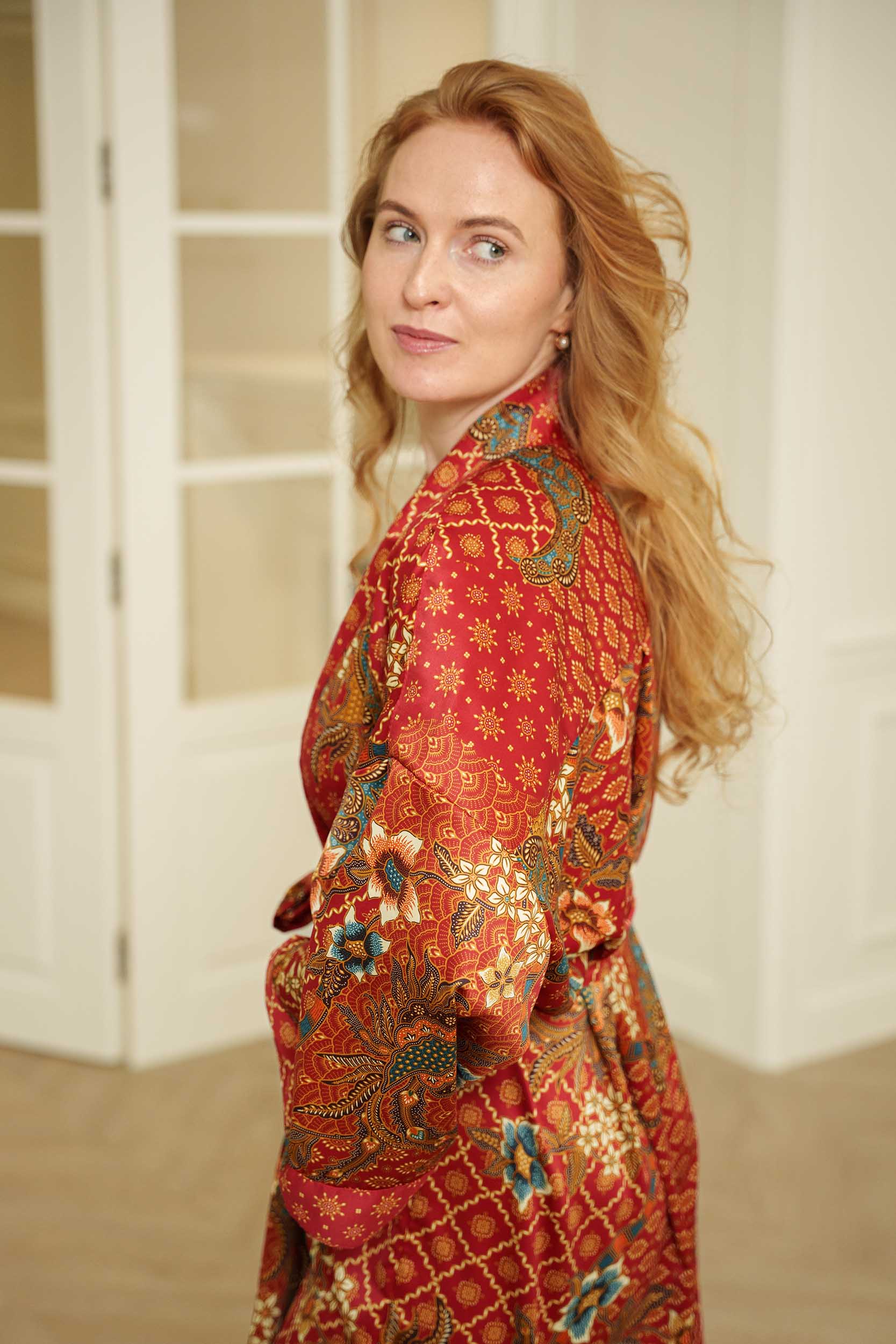 Side view of Toré Senja women’s kimono robe – elegant red satin robe with Indonesian-inspired pattern.