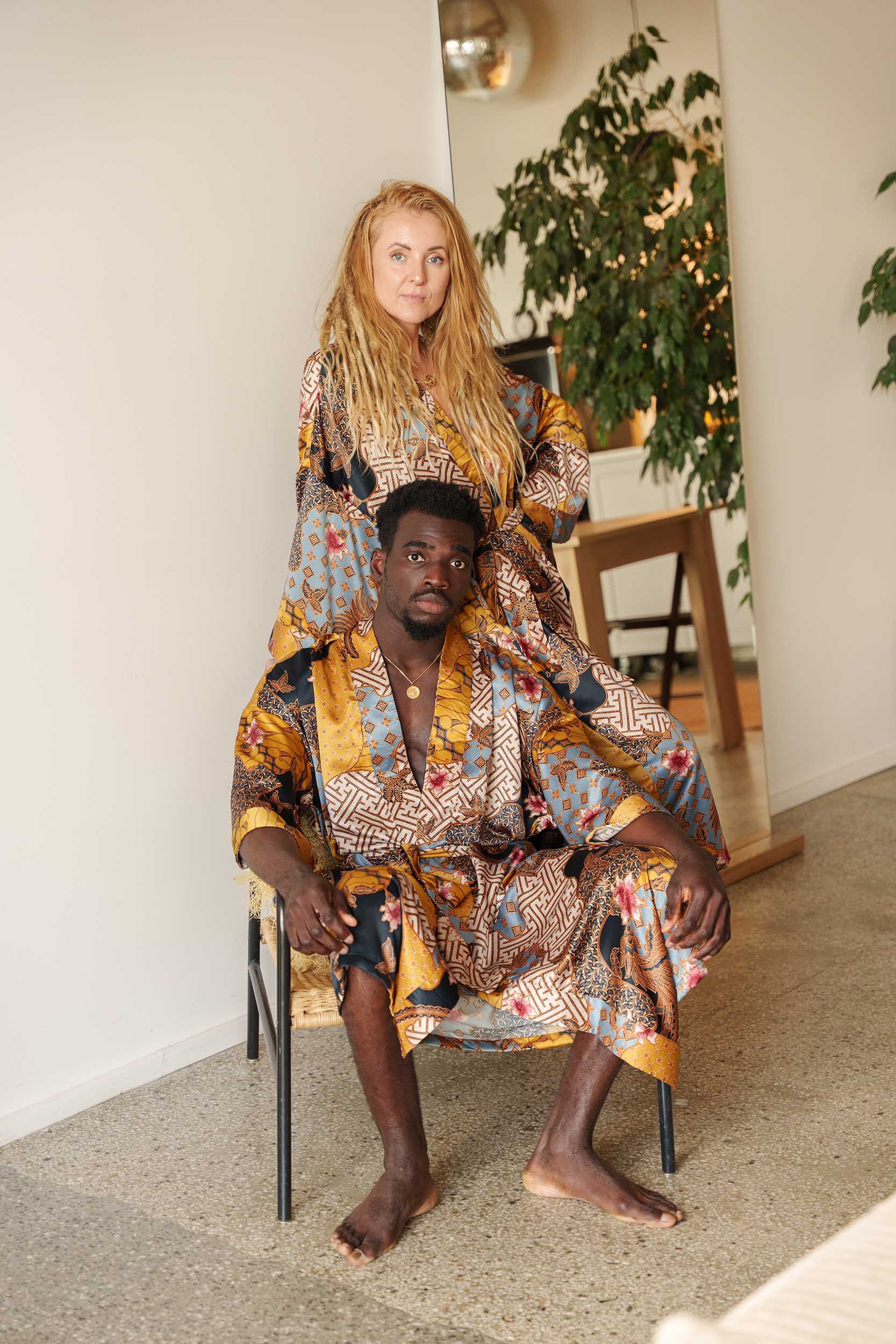 Couple wearing matching Toré Sorga kimono robes – yellow and blue satin dressing gowns inspired by Balinese paradise.