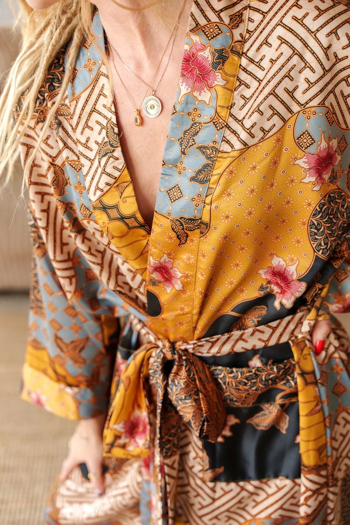 Close-up of Toré Sorga robe fabric – soft satin with intricate blue and gold batik pattern.