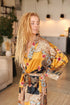 Woman wearing a Sorga satin kimono robe in a room with plants.