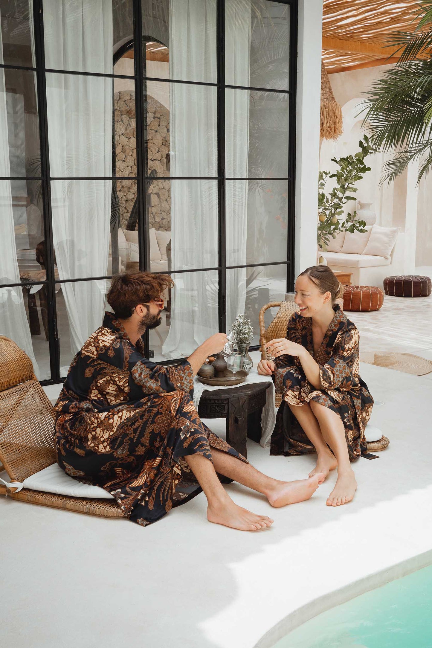 Man and woman in Toré Svarna robes – elegant couple kimono set in luxury satin fabric.