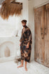 Man wearing Toré Svarna kimono robe – long black and gold satin dressing gown with batik pattern.