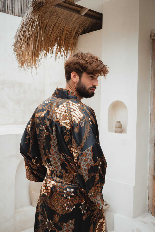 Close-up of Toré Svarna robe fabric – black satin with intricate bronze and gold batik print.